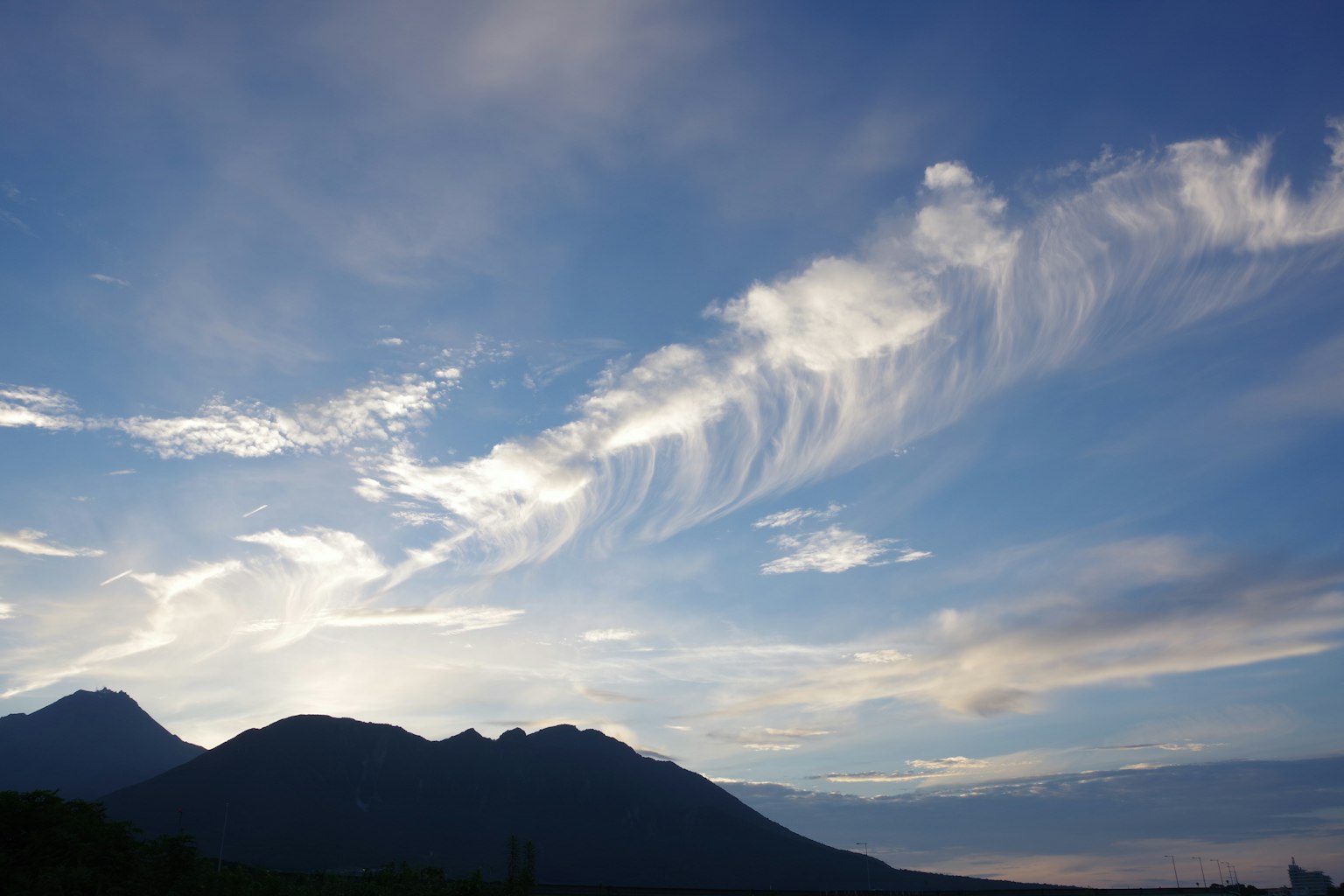 Une vue pittoresque avec un ciel bleu et des nuages blancs sur des silhouettes de montagnes