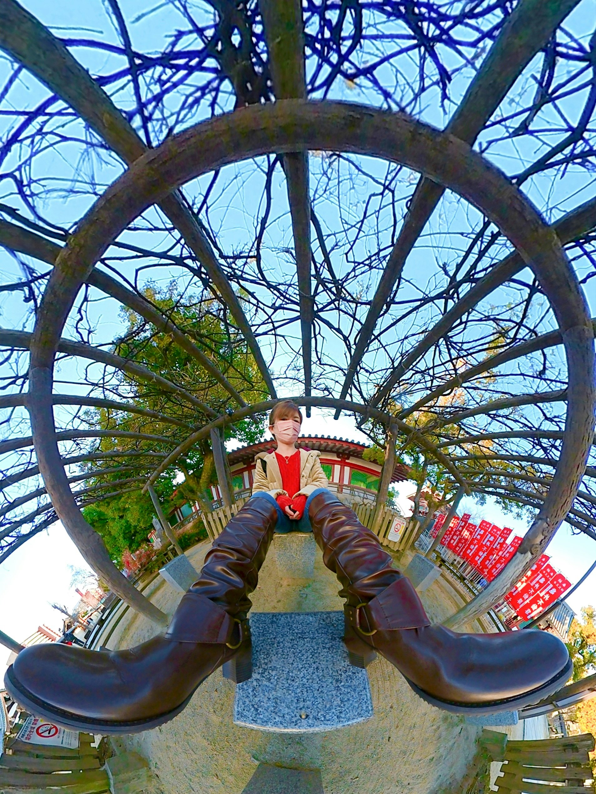 aire de jeux extérieure avec grande roue en bois et un enfant qui regarde vers le haut