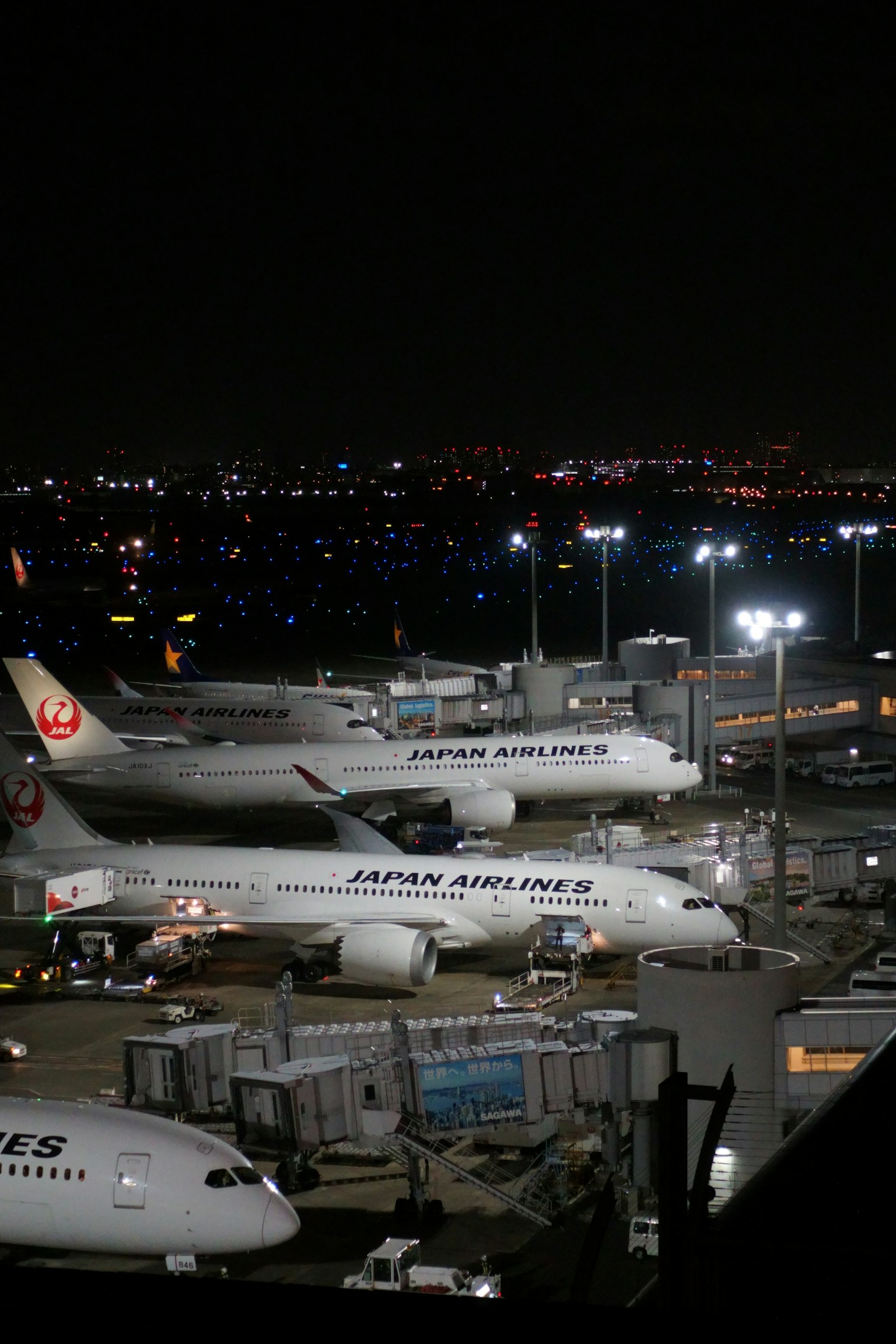 夜の空港に停まる複数の航空機と明るい照明