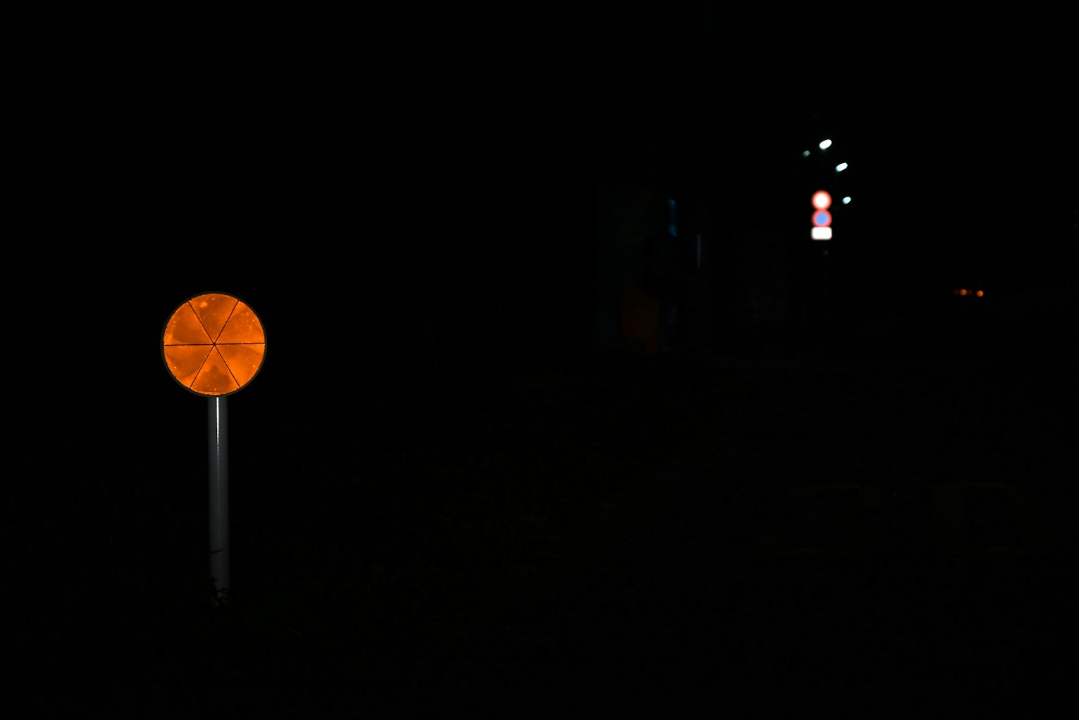 An orange traffic sign illuminated against a dark background