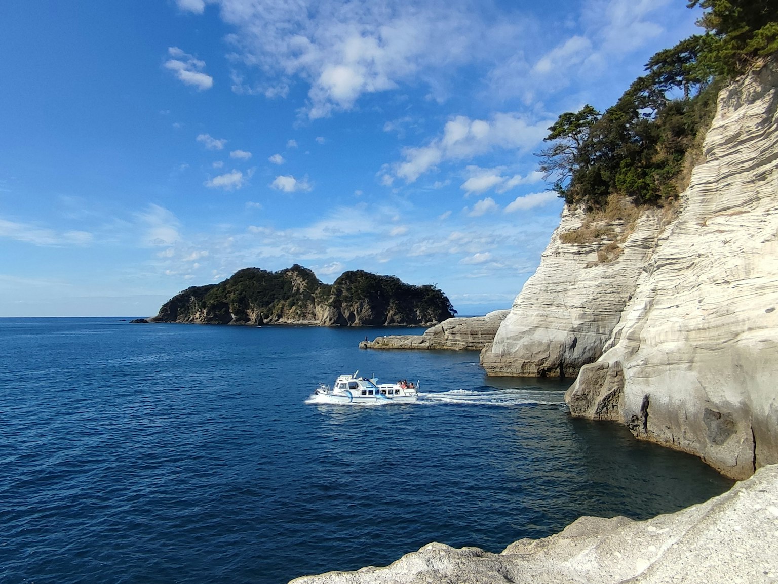 Pemandangan indah lautan biru dengan tebing putih pulau kecil dan perahu