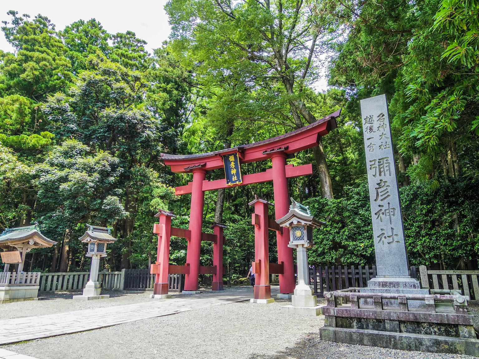 Pintu masuk kuil dengan gerbang torii merah dan monumen batu