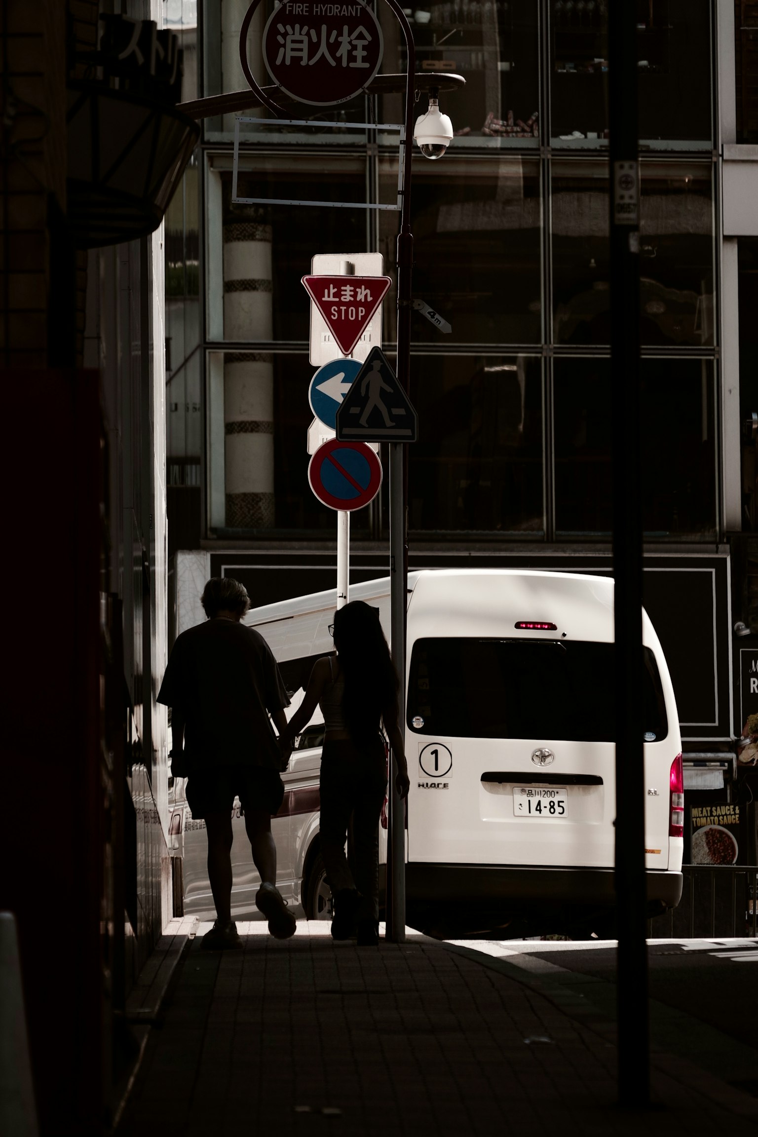 Silhouettes de deux personnes debout avec une camionnette blanche et des panneaux de circulation en arrière-plan