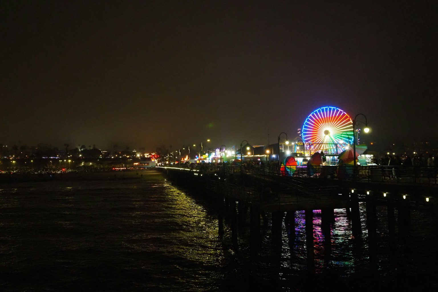 Grande roue et lumières colorées brillant sur la jetée la nuit au bord de la mer