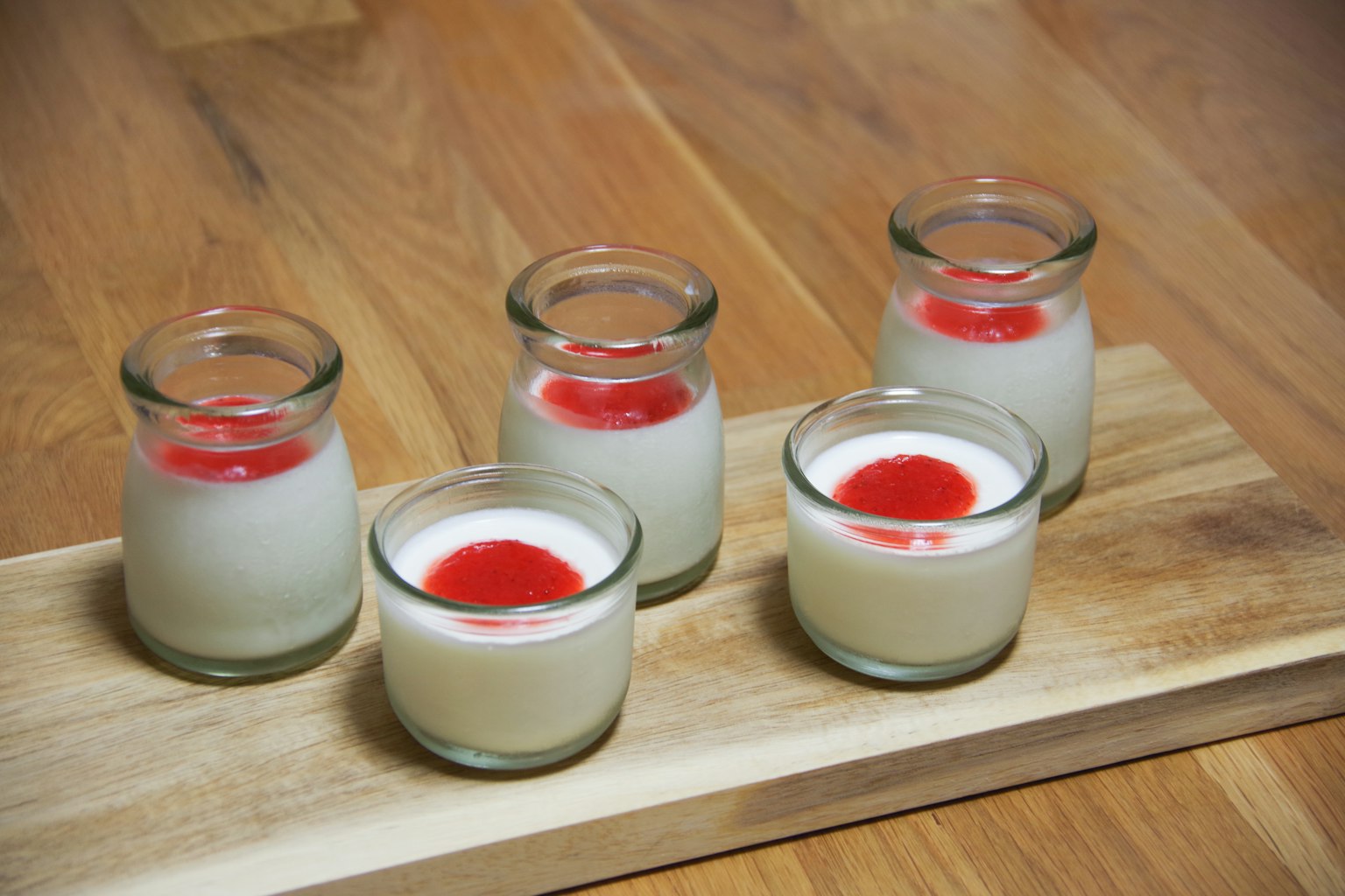 Kumpulan makanan penutup dalam wadah kaca kecil dengan tekstur krim dan topping merah