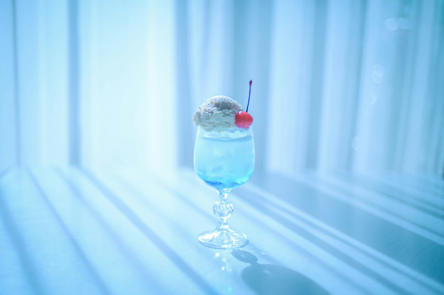 一杯蓝色鸡尾酒，上面放着冰淇淋和樱桃