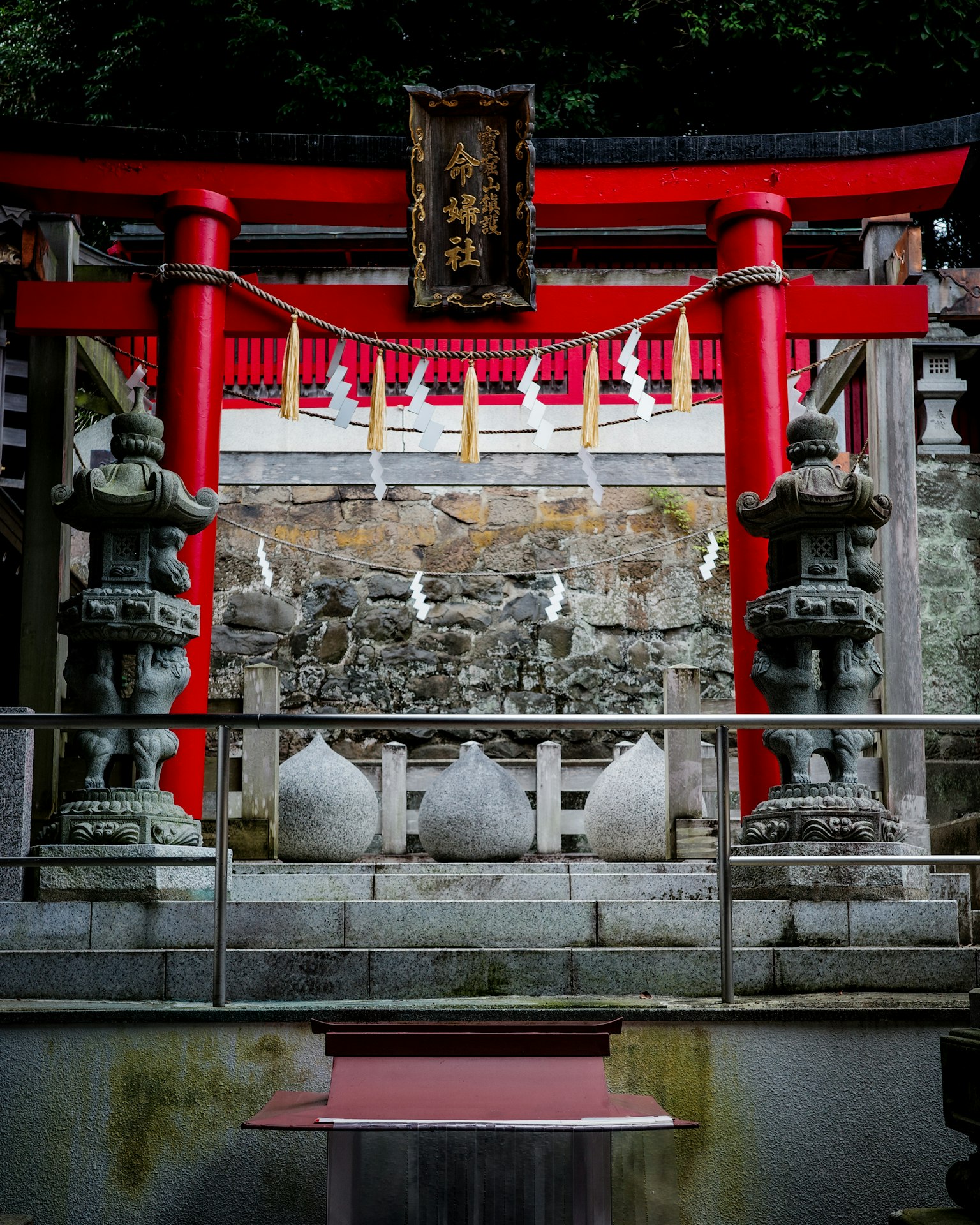 Ingresso di un santuario con un torii rosso e statue di pietra