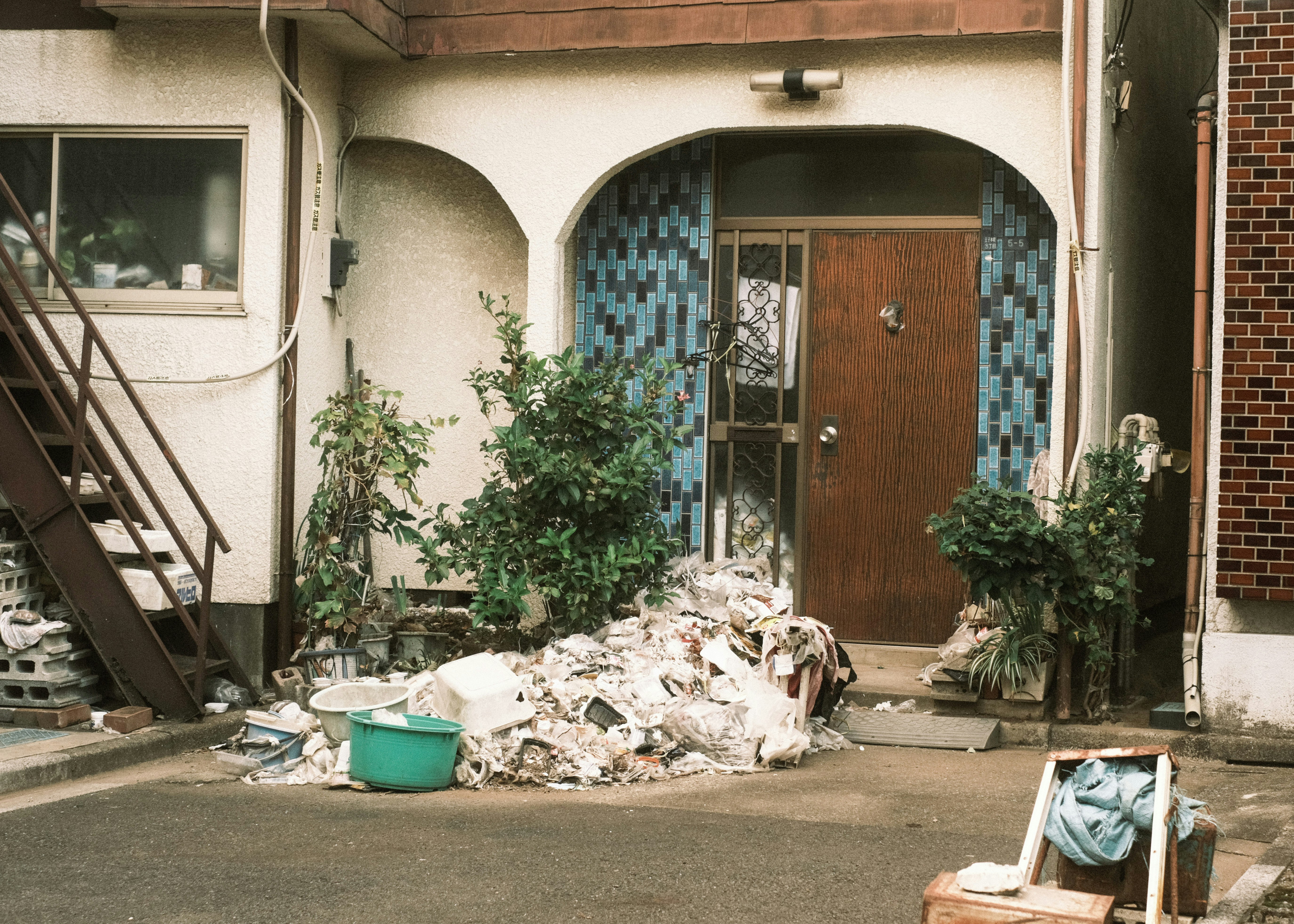 entrée d’une ruelle avec des débris et des plantes en pots