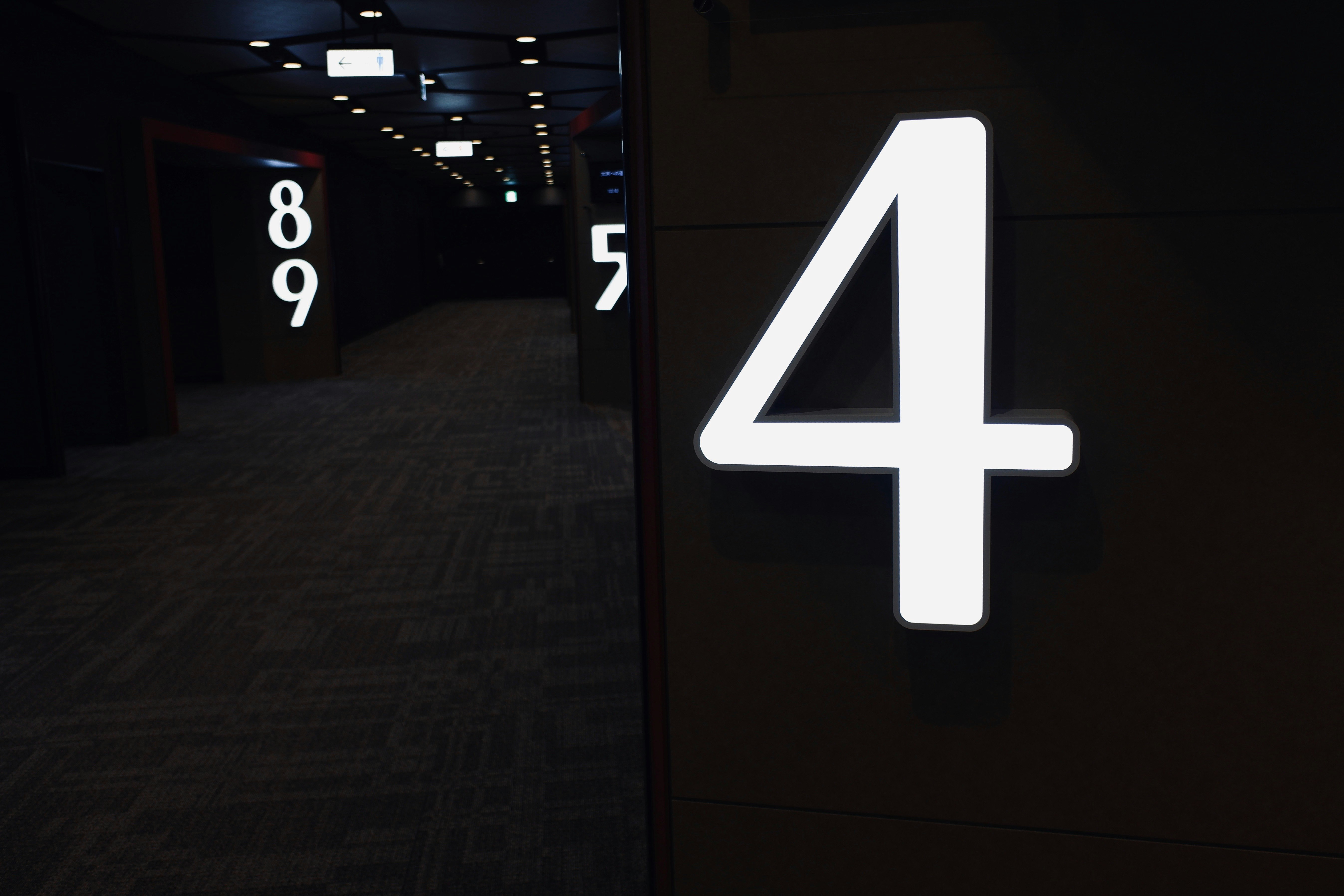 暗い廊下の壁に光る「4」の番号プレート