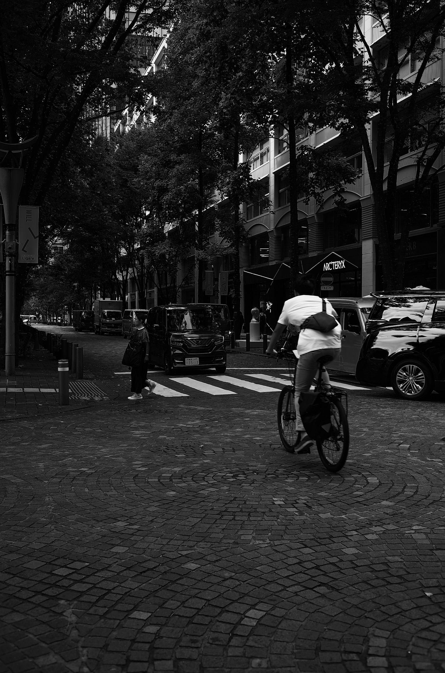 Una persona montando una bicicleta en una intersección de la ciudad en blanco y negro
