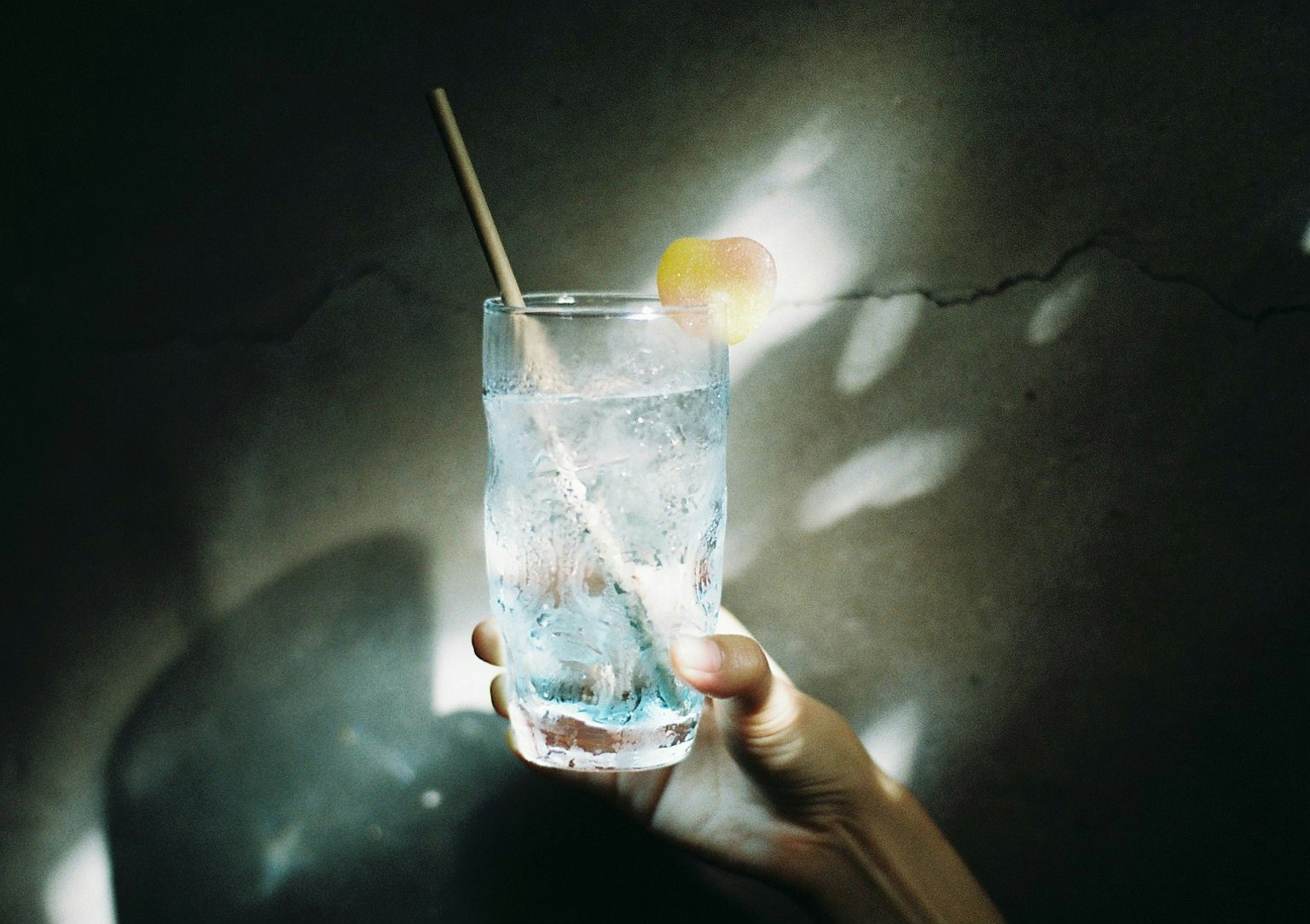 一隻手握著裝有冰塊和檸檬片的透明玻璃杯