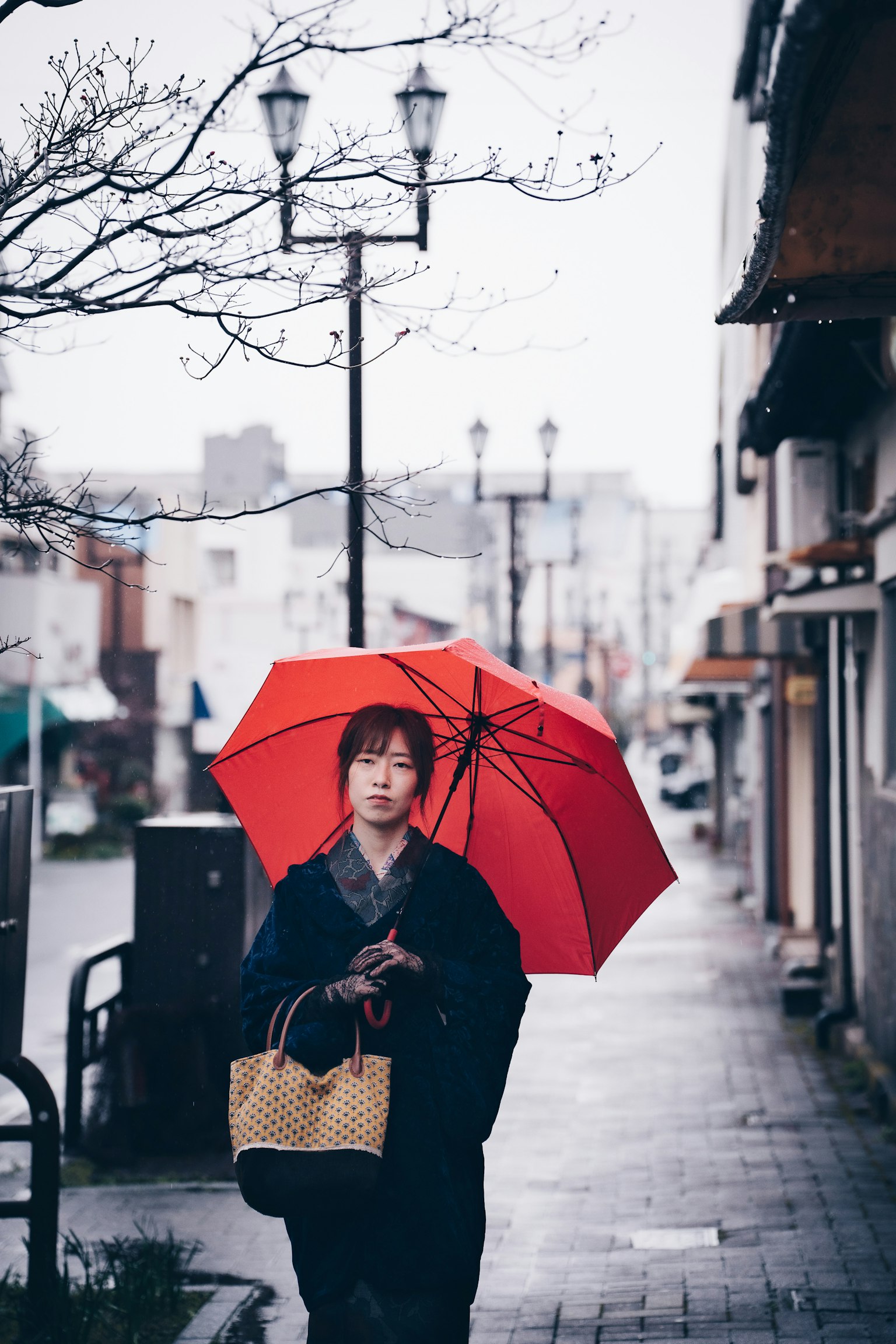 一位女性在街上走，手持红伞