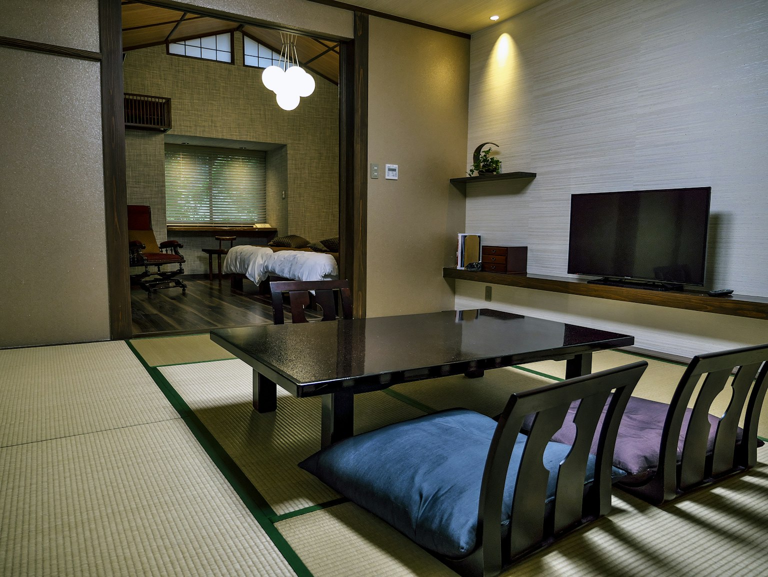 Innenraum eines traditionellen japanischen Zimmers mit Tisch und Kissen Schlafzimmer im Hintergrund sichtbar
