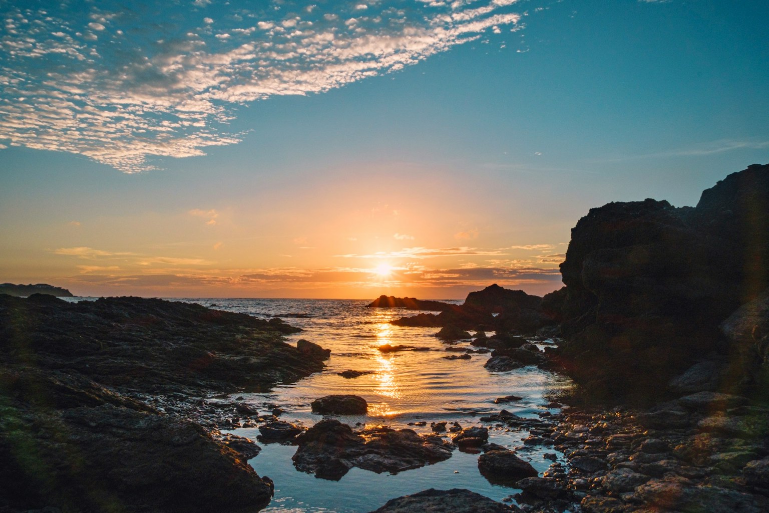 海上日落的美丽景观，岩石海岸和水面的倒影