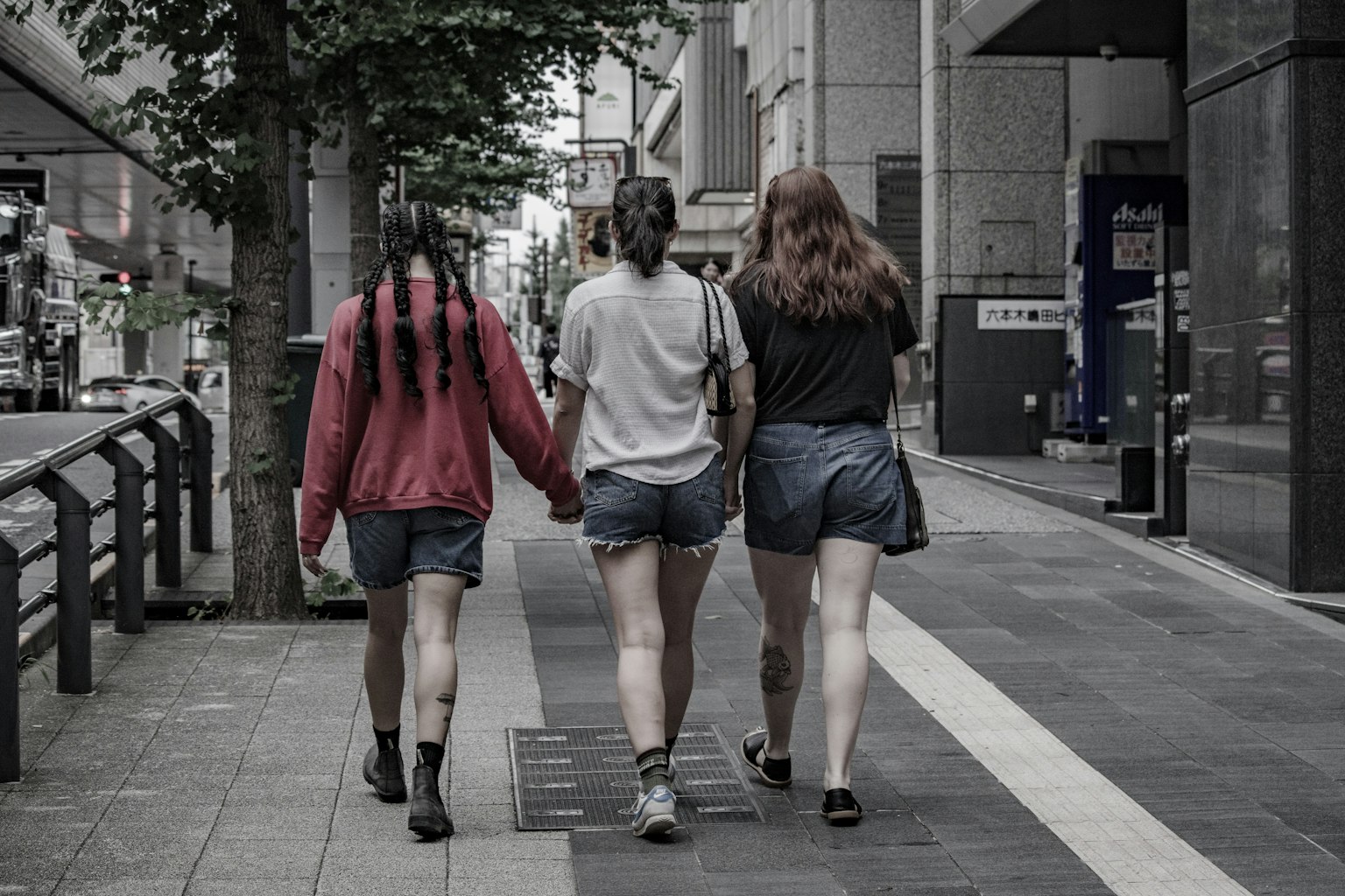Three women walking hand in hand on a city street