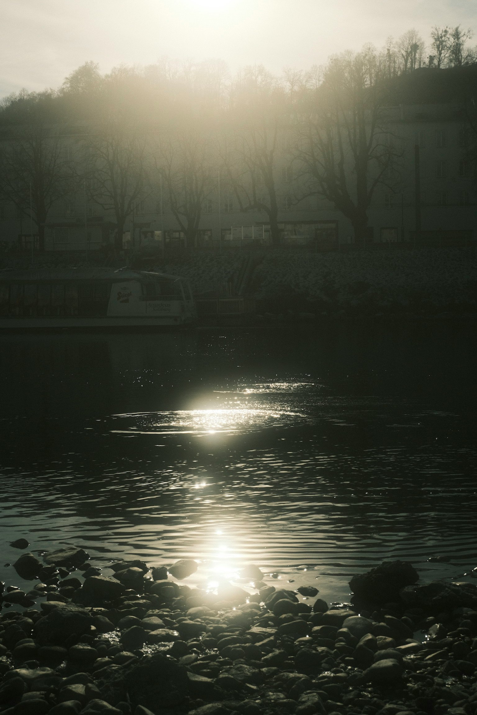 Douce lumière du soleil se reflétant sur la surface de l'eau avec un rivage rocheux