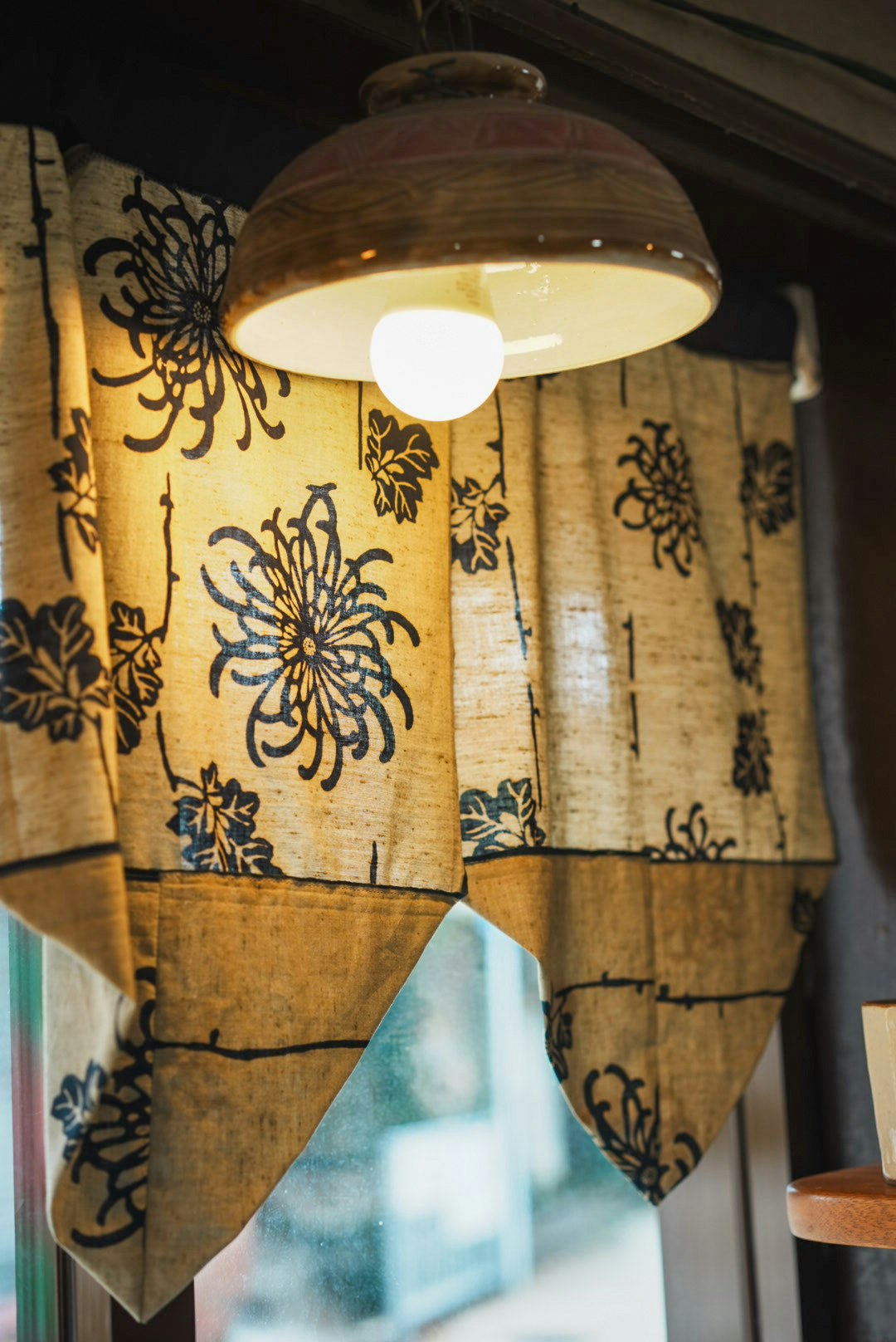 Cozy interior featuring floral patterned curtains and a pendant light