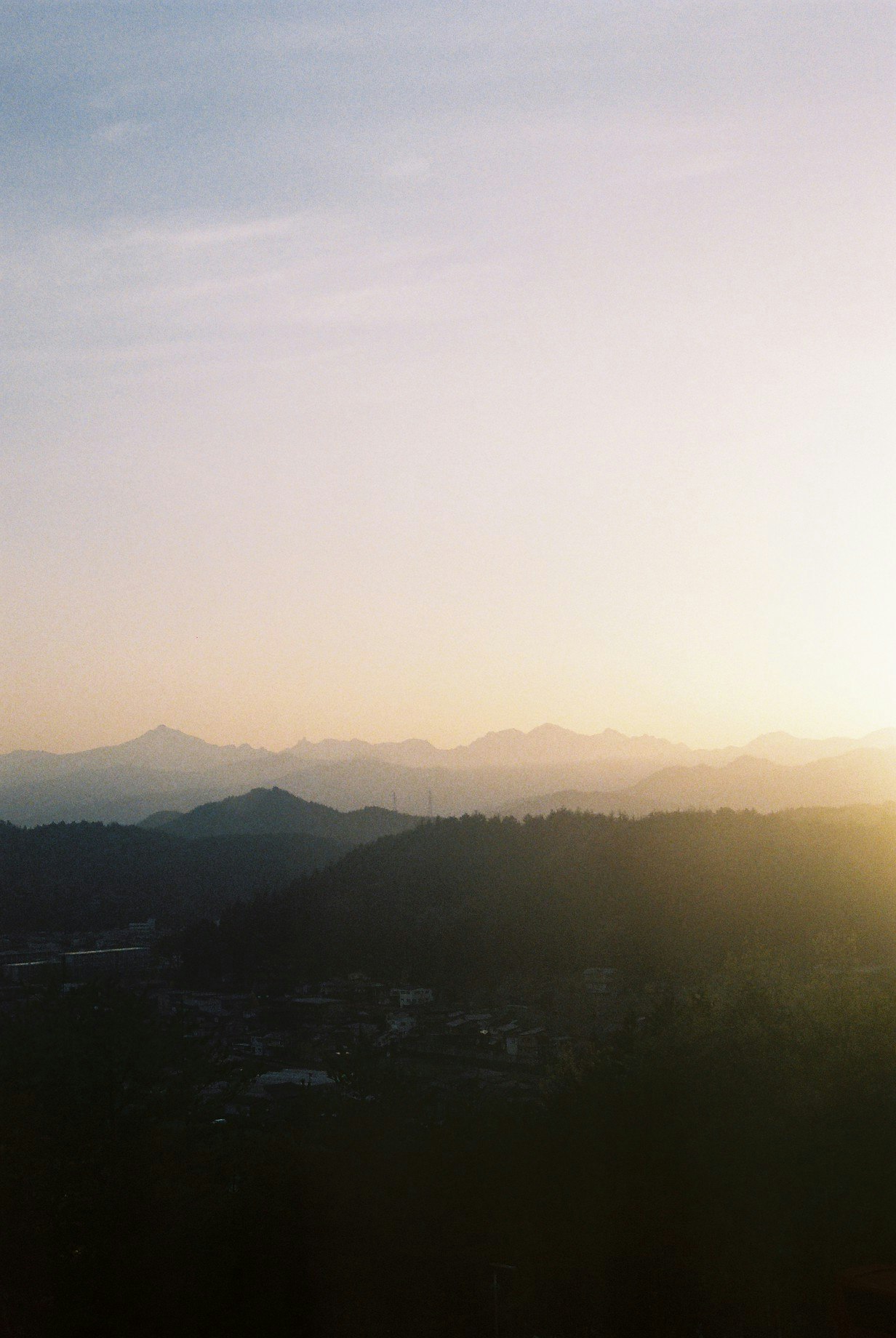夕日に照らされる山並みと霧のかかった谷の風景
