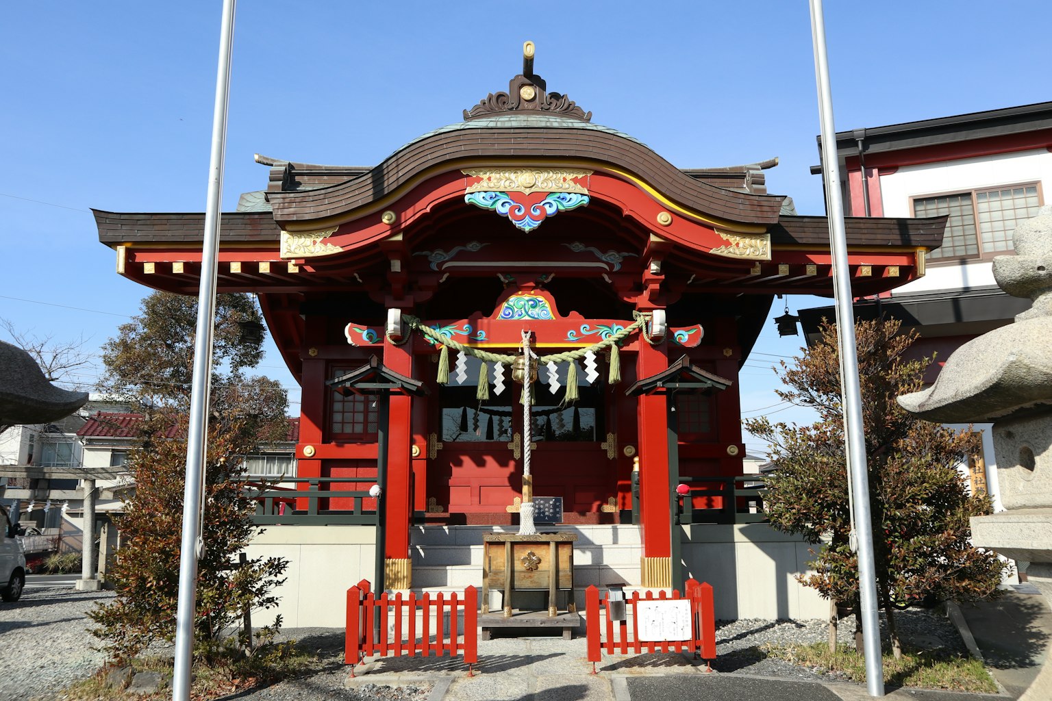 A shrine building with a red roof surrounded by trees