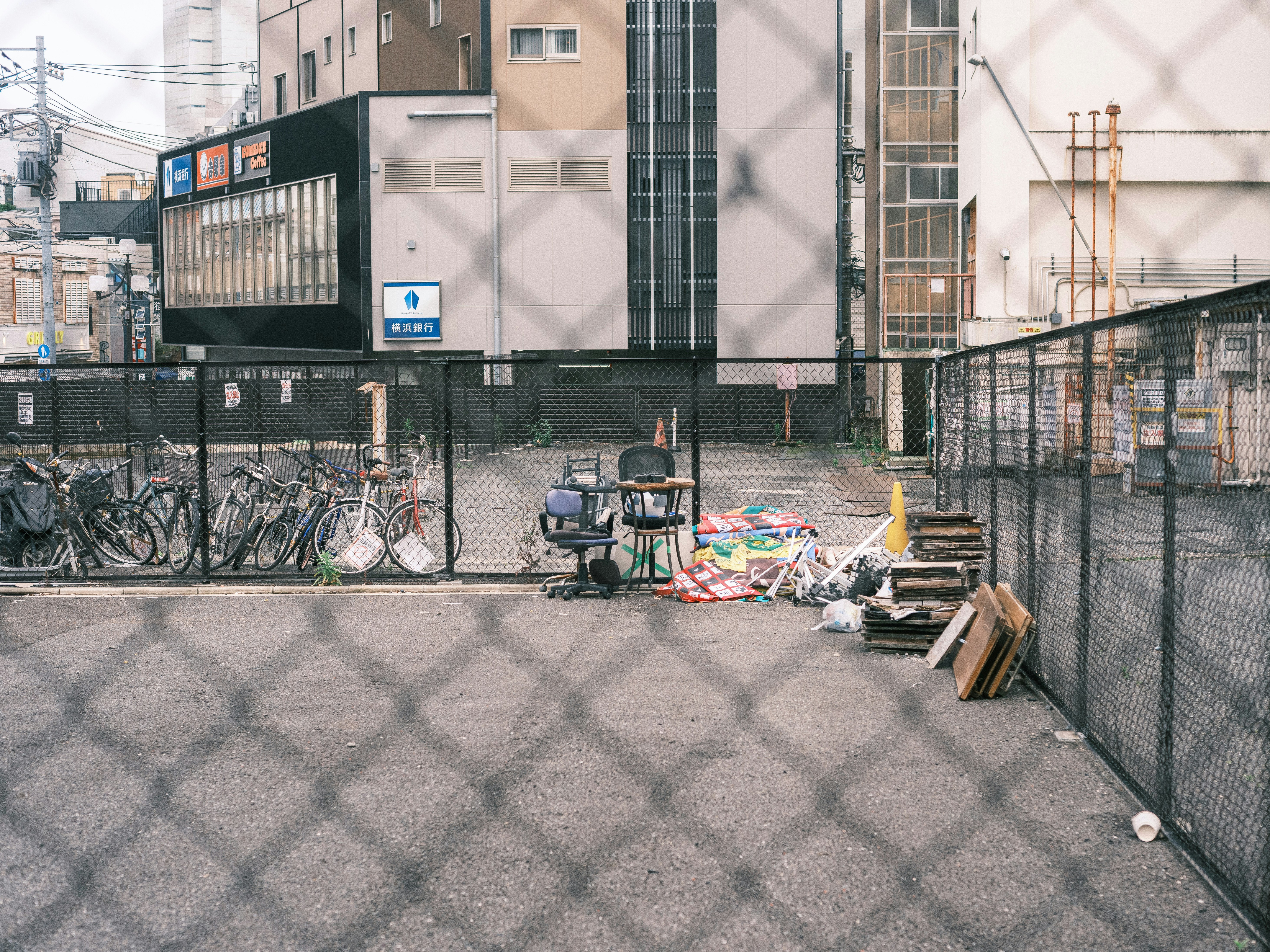 自転車が並ぶ路地のフェンス沿いにある段ボールと荷物