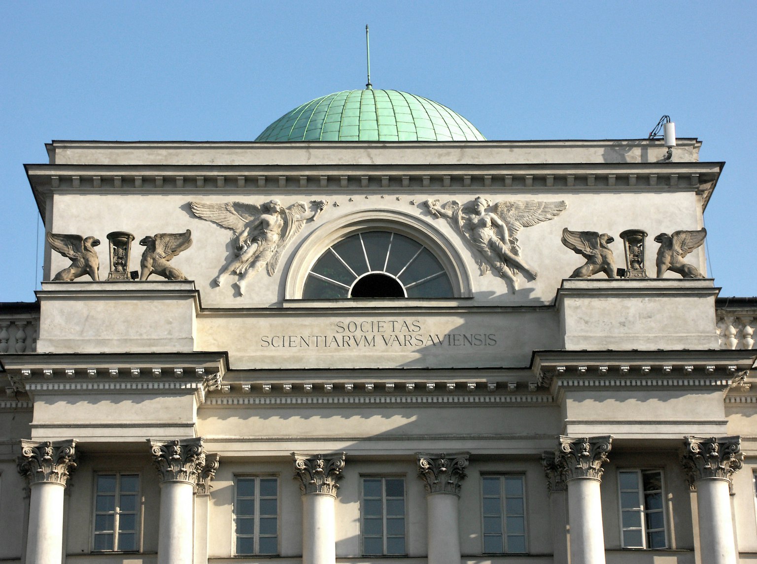 Facciata di un grande edificio con una cupola verde e sculture decorative