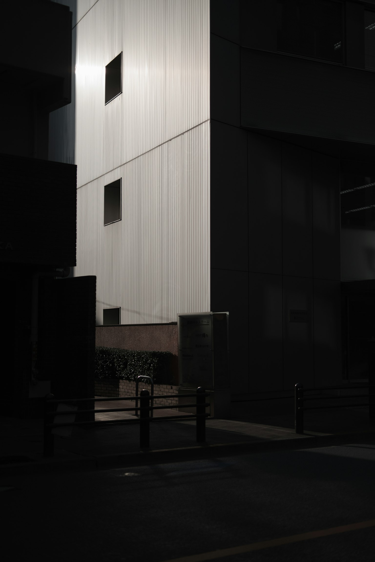 Contraste entre un bâtiment à mur blanc et un bâtiment noir dans une rue faiblement éclairée la nuit