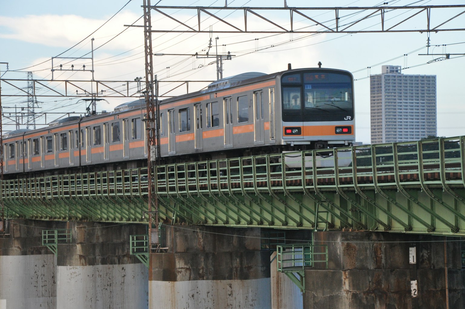 Train crossing a bridge with a city skyline in the background