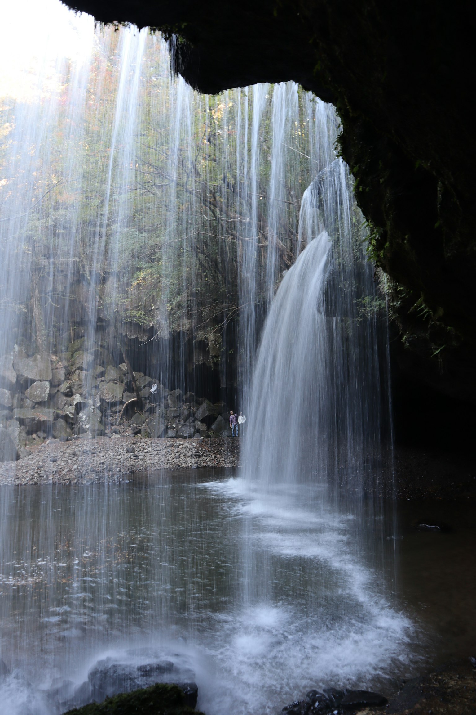 Pemandangan indah dengan air terjun yang mengalir Kabut yang naik dari permukaan air Dikelilingi batu hijau di lingkungan yang tenang