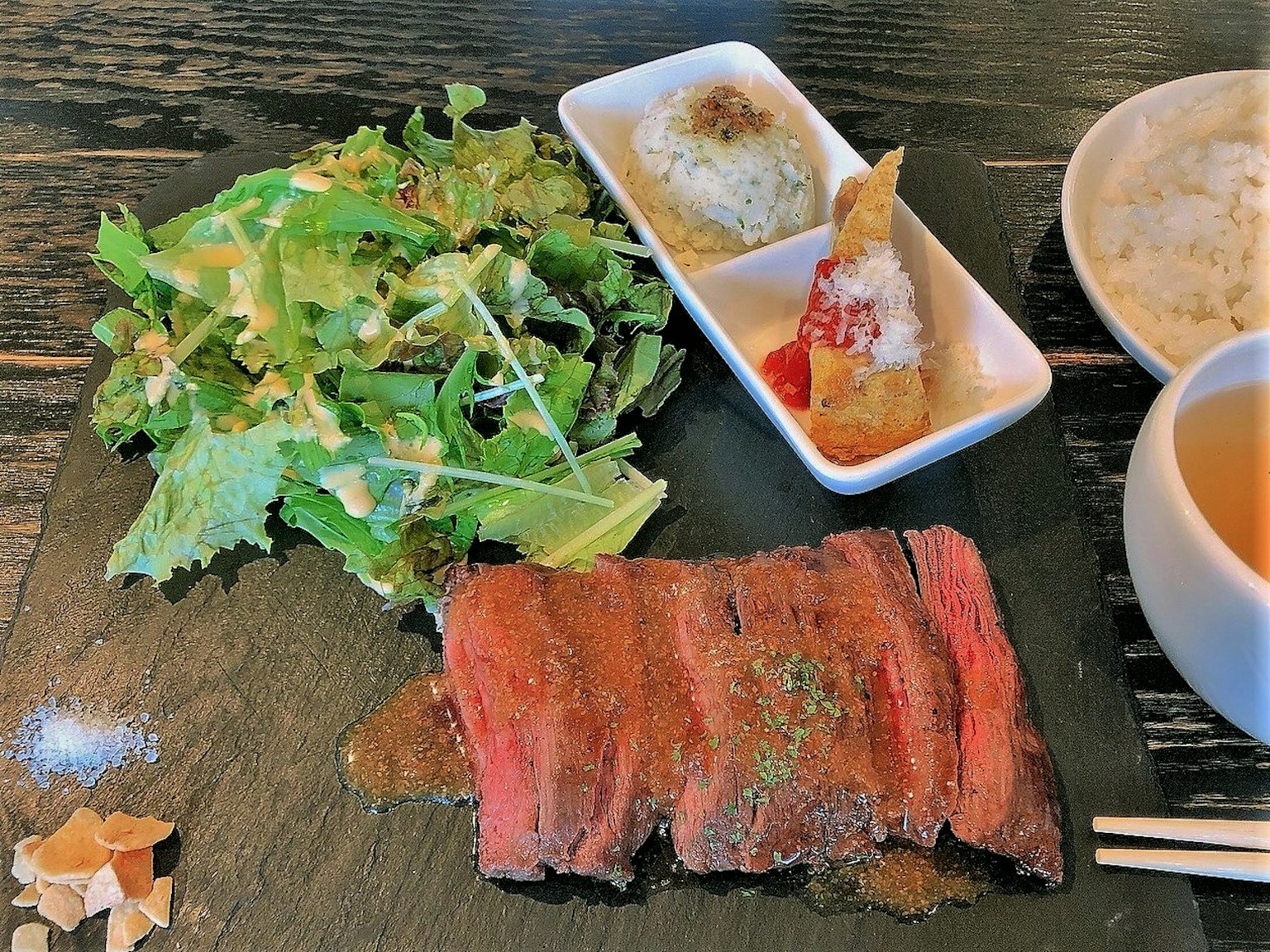 Plato de carne de res en rodajas servido con ensalada y guarniciones pequeñas