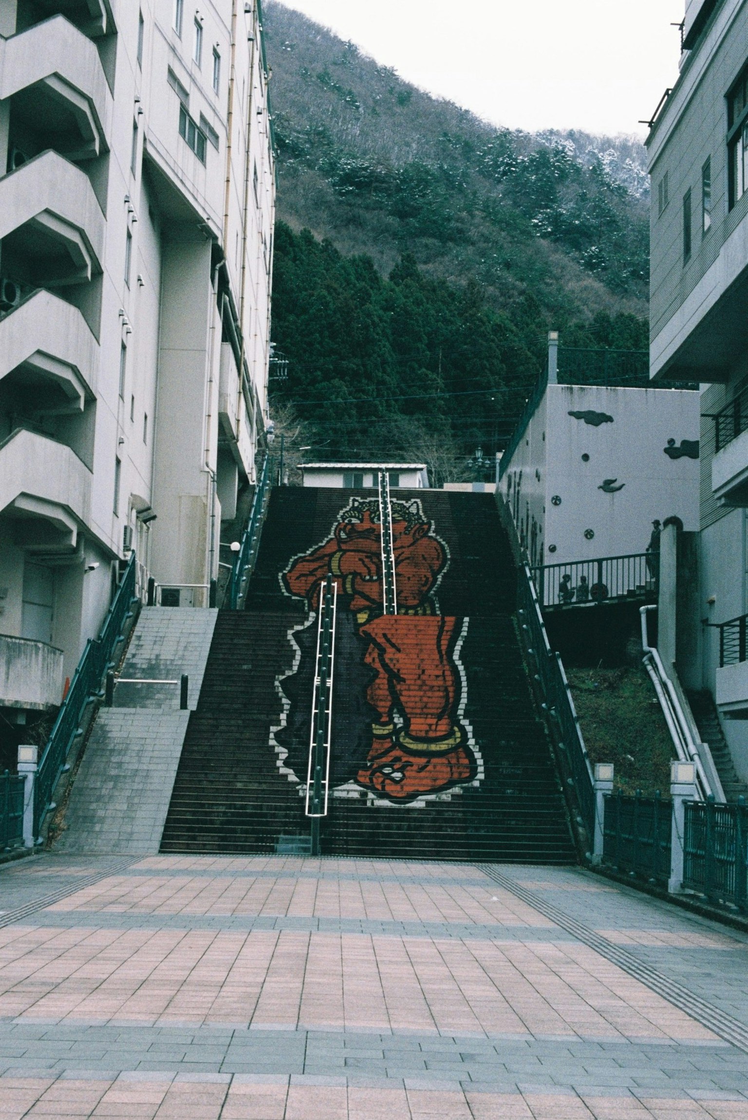 Arte di strada con un grande piede rosso su scale e edifici circostanti
