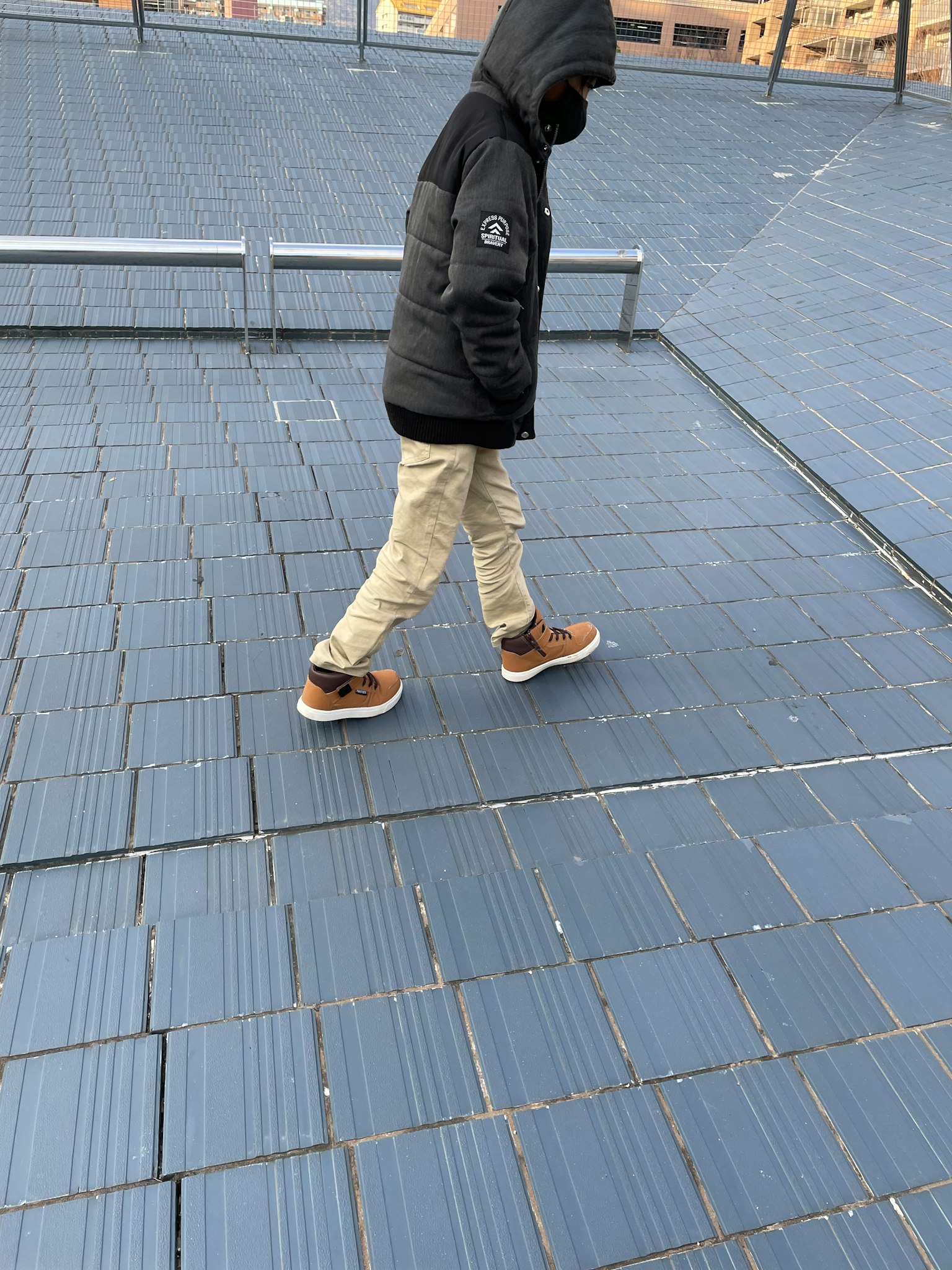 在屋顶上走的人的轮廓，穿着黑色夹克和卡其裤