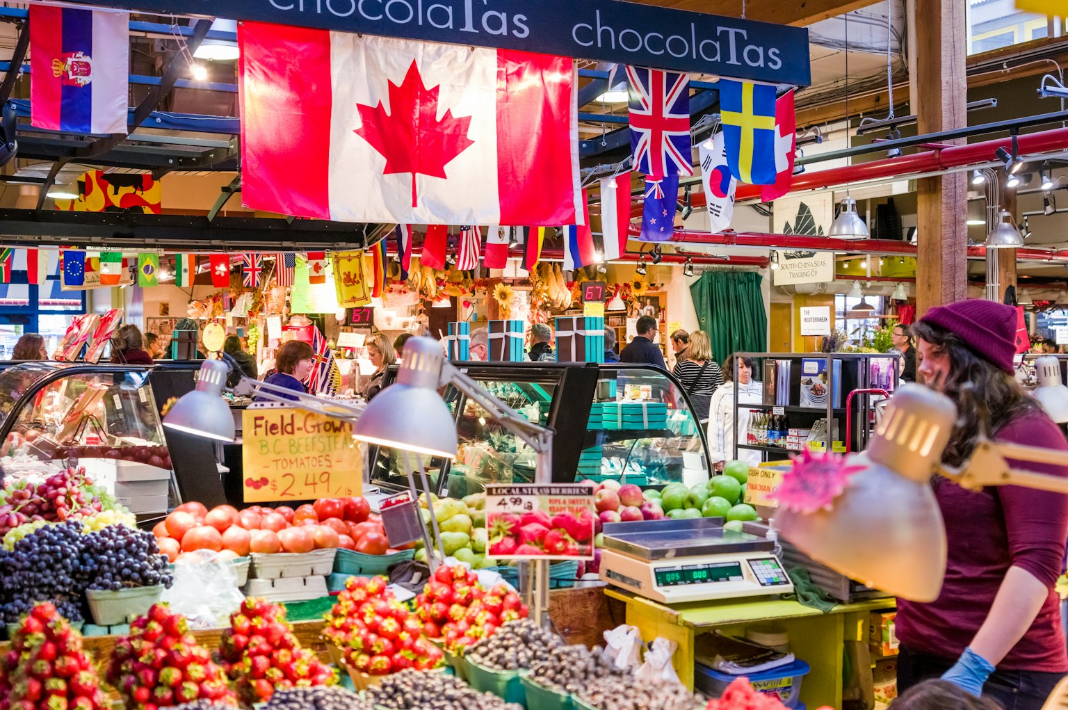 Une scène de marché dynamique avec des fruits et légumes frais et des drapeaux canadiens et internationaux affichés