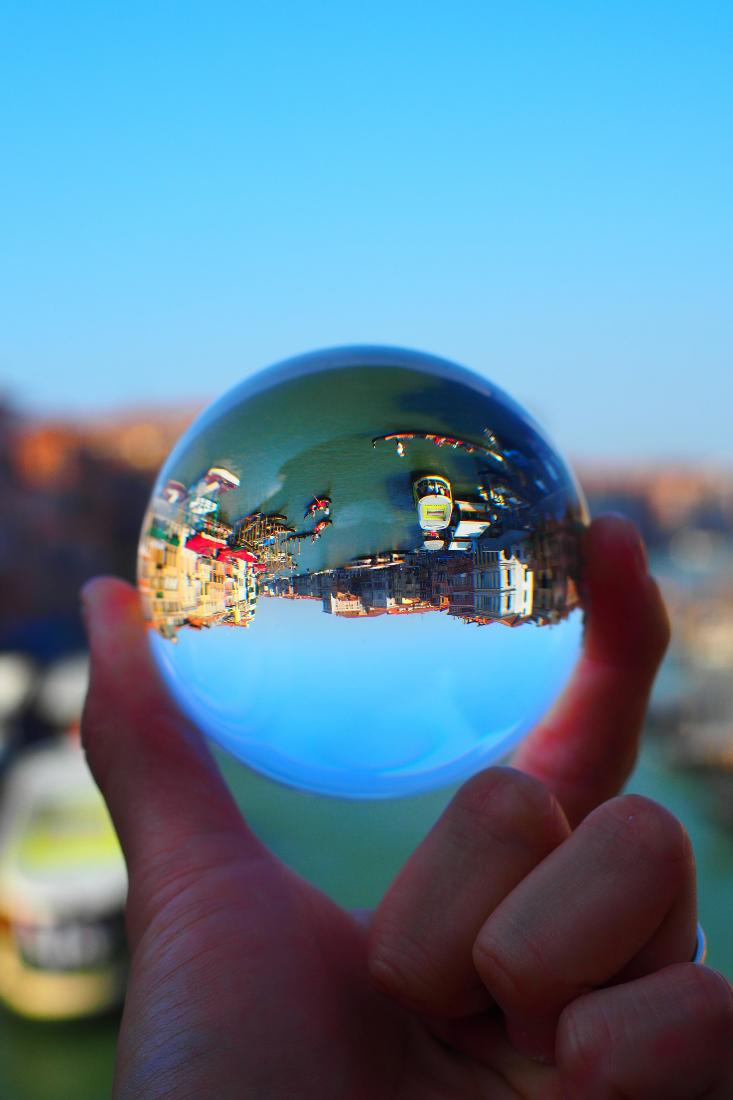 street scene reflected in a transparent sphere held in hands