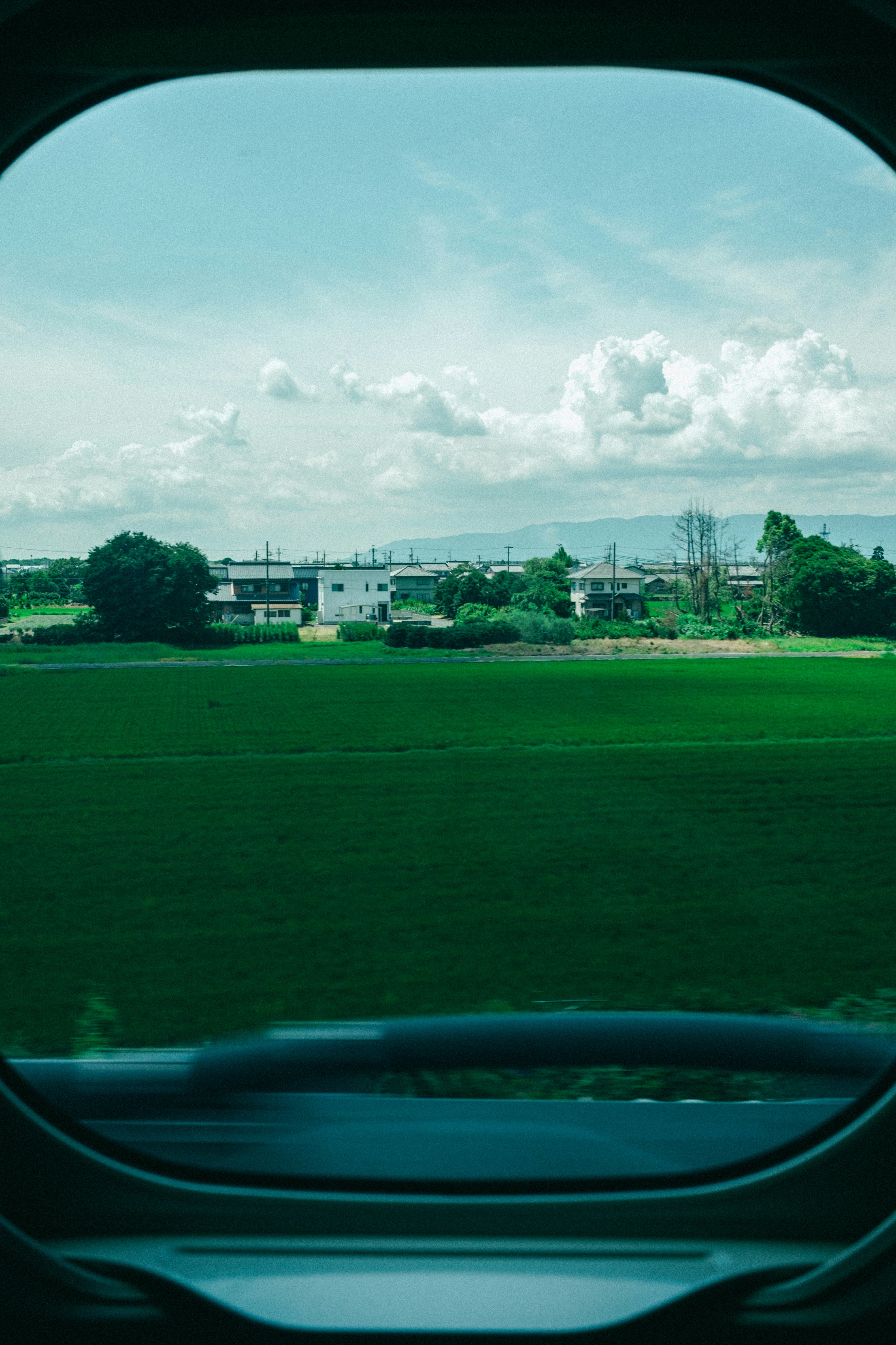 green countryside landscape with cloudy sky seen through a window