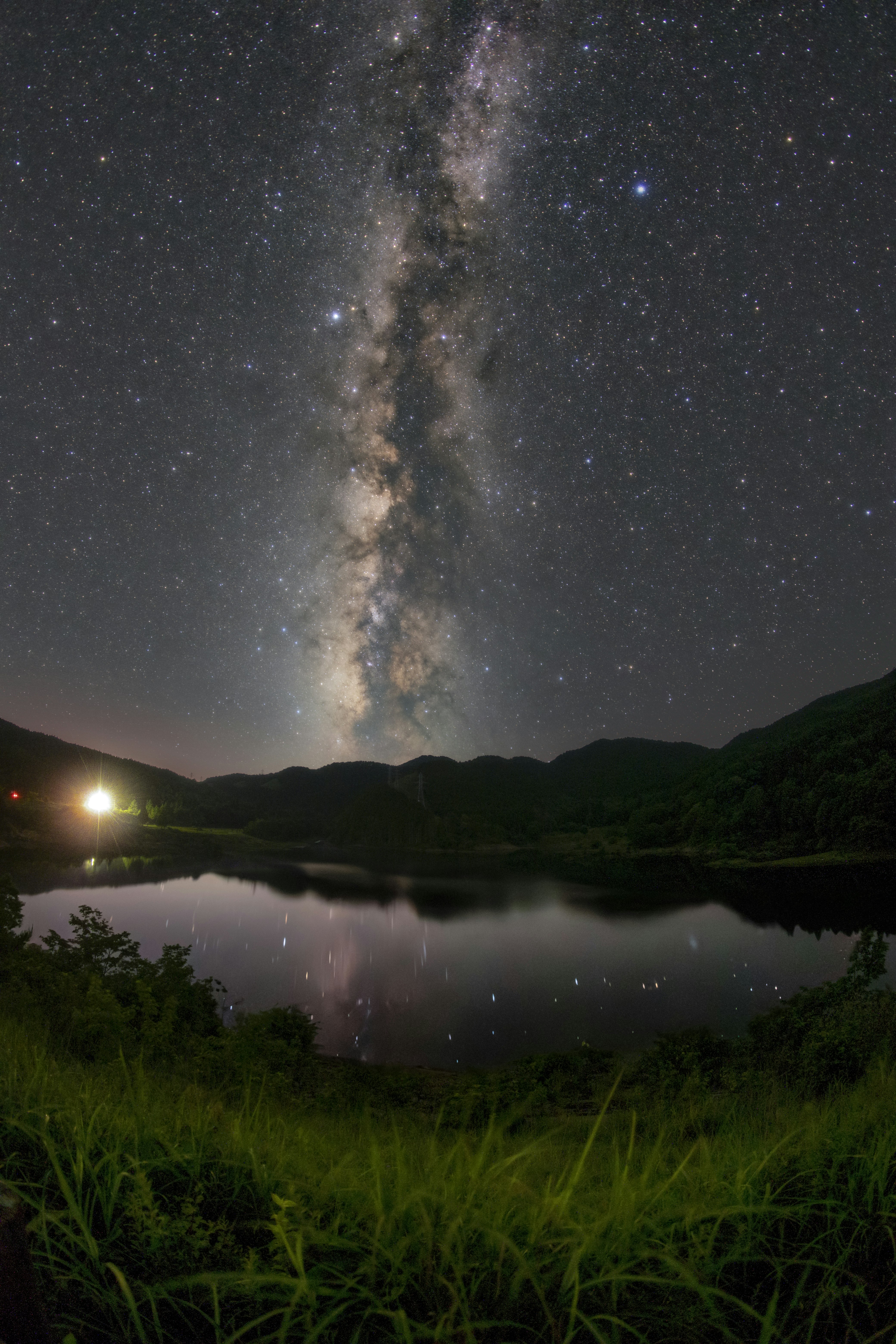 夜空に伸びる天の川と湖畔の静かな風景