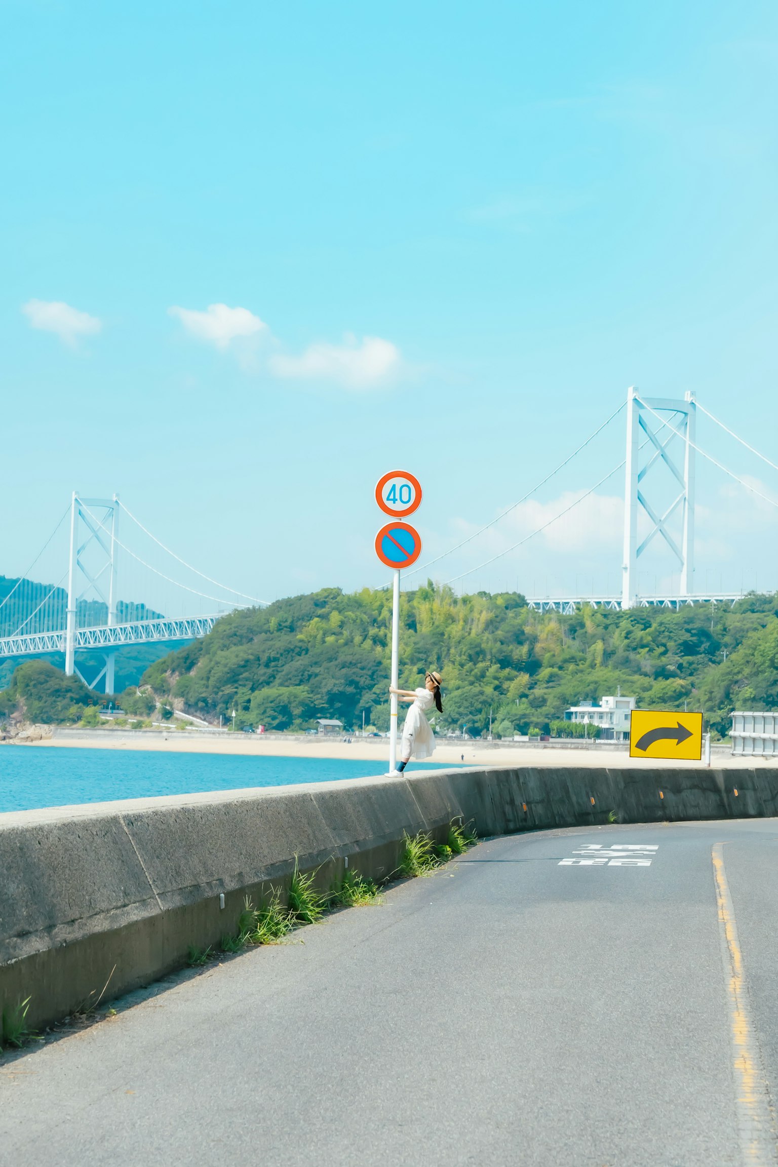 Une vue pittoresque d'une route bordée par la mer avec des panneaux de signalisation et un pont en arrière-plan