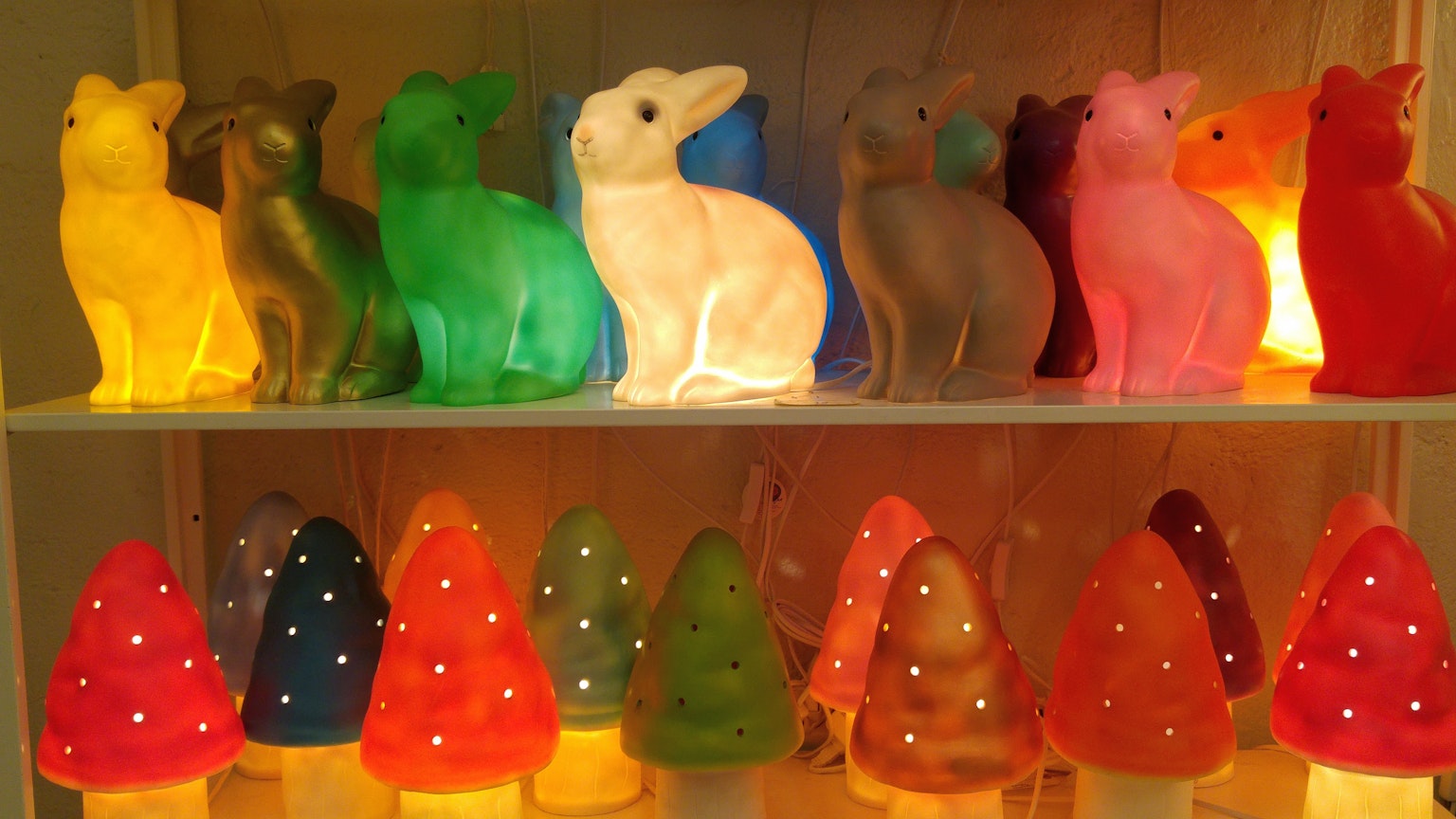 Colorful rabbit lamps displayed on a shelf with glowing mushroom-shaped lamps