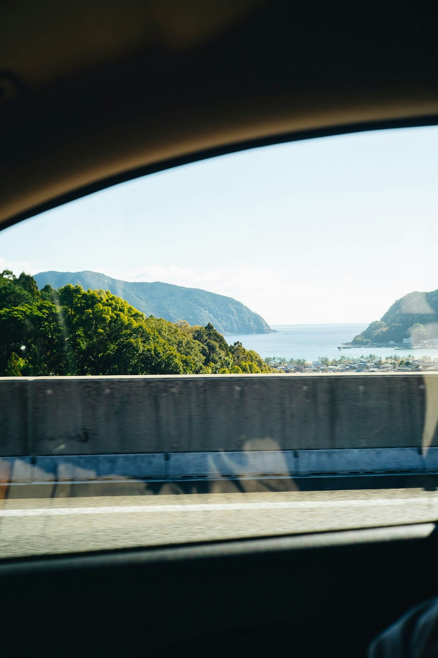 Pemandangan pantai dan pegunungan dari jendela mobil