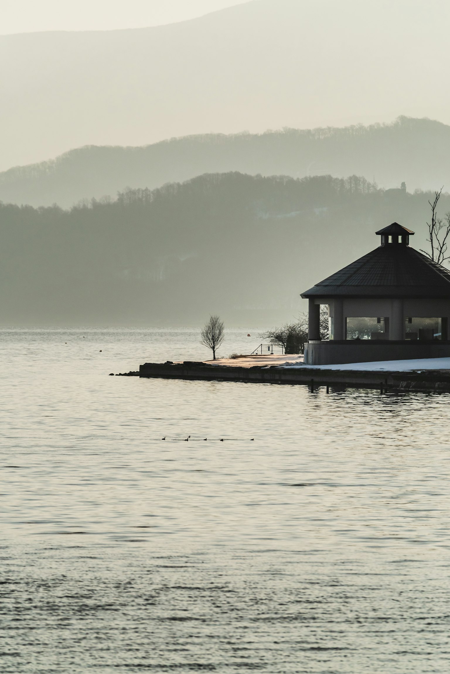 Gazebo tenang di tepi danau dengan pegunungan di latar belakang