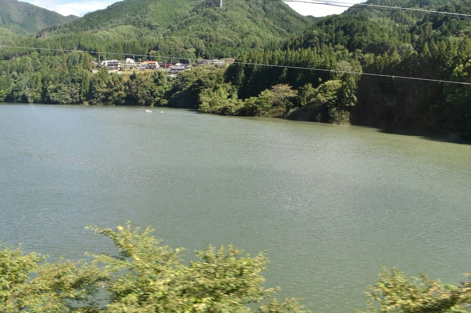 Danau tenang dikelilingi oleh gunung hijau