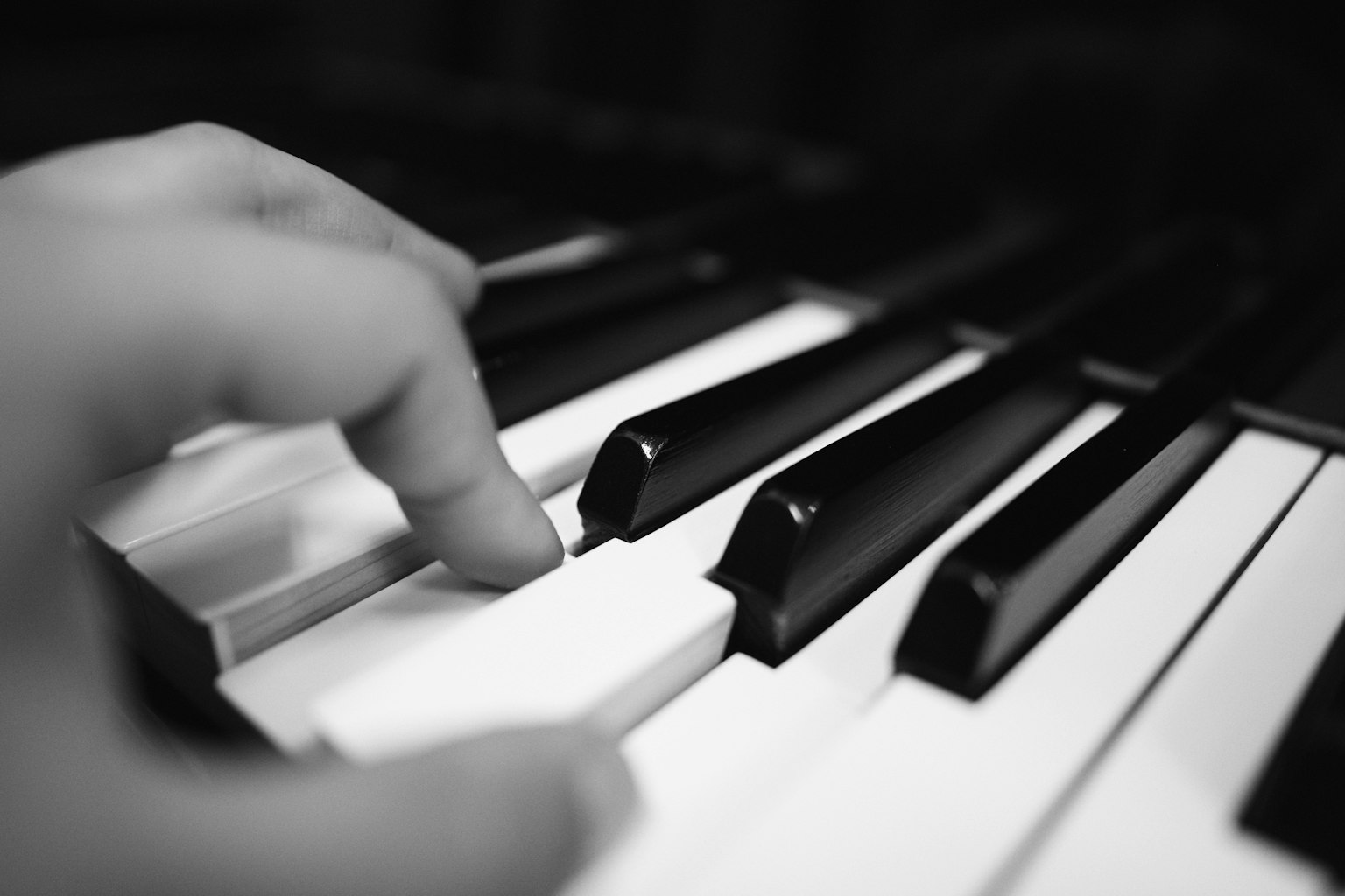 Primo piano di una mano che tocca i tasti del pianoforte
