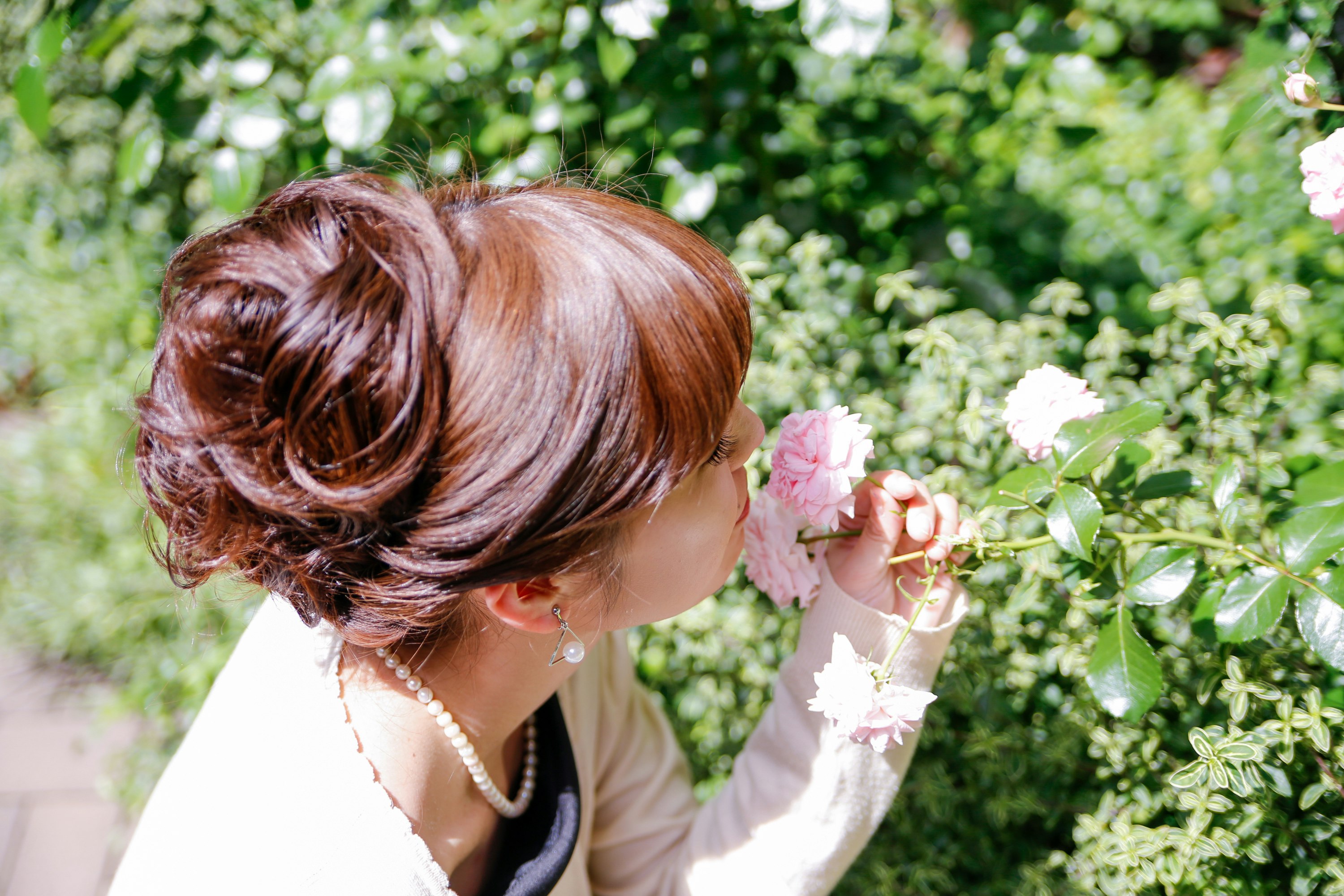 花を手に微笑む女性のヘアアレンジと花束のある屋外シーン