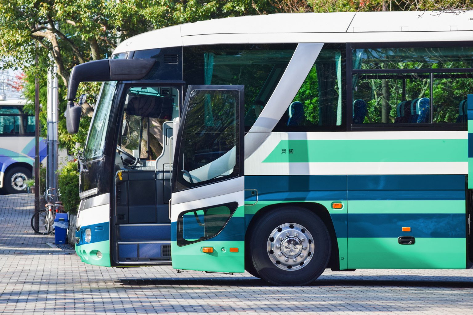 Un autobús de rayas verdes y blancas estacionado en un lugar soleado