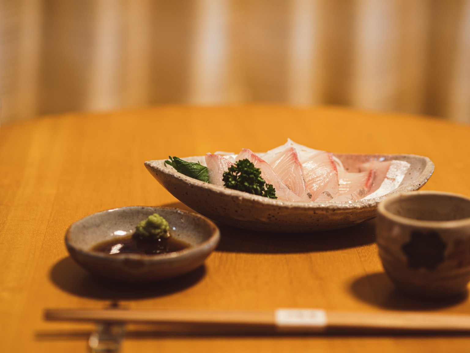 Sashimi servido en una mesa de madera con wasabi y salsa de soja