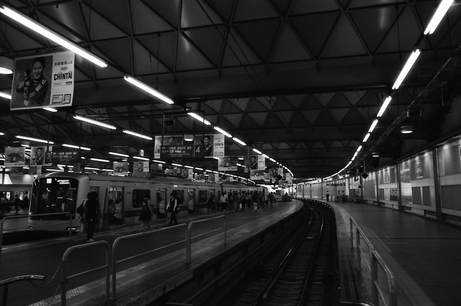 Black and white photo of a train station featuring platforms and curved tracks