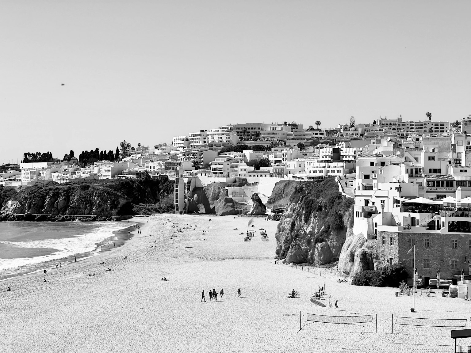 Black and white coastal view featuring buildings and sandy beach