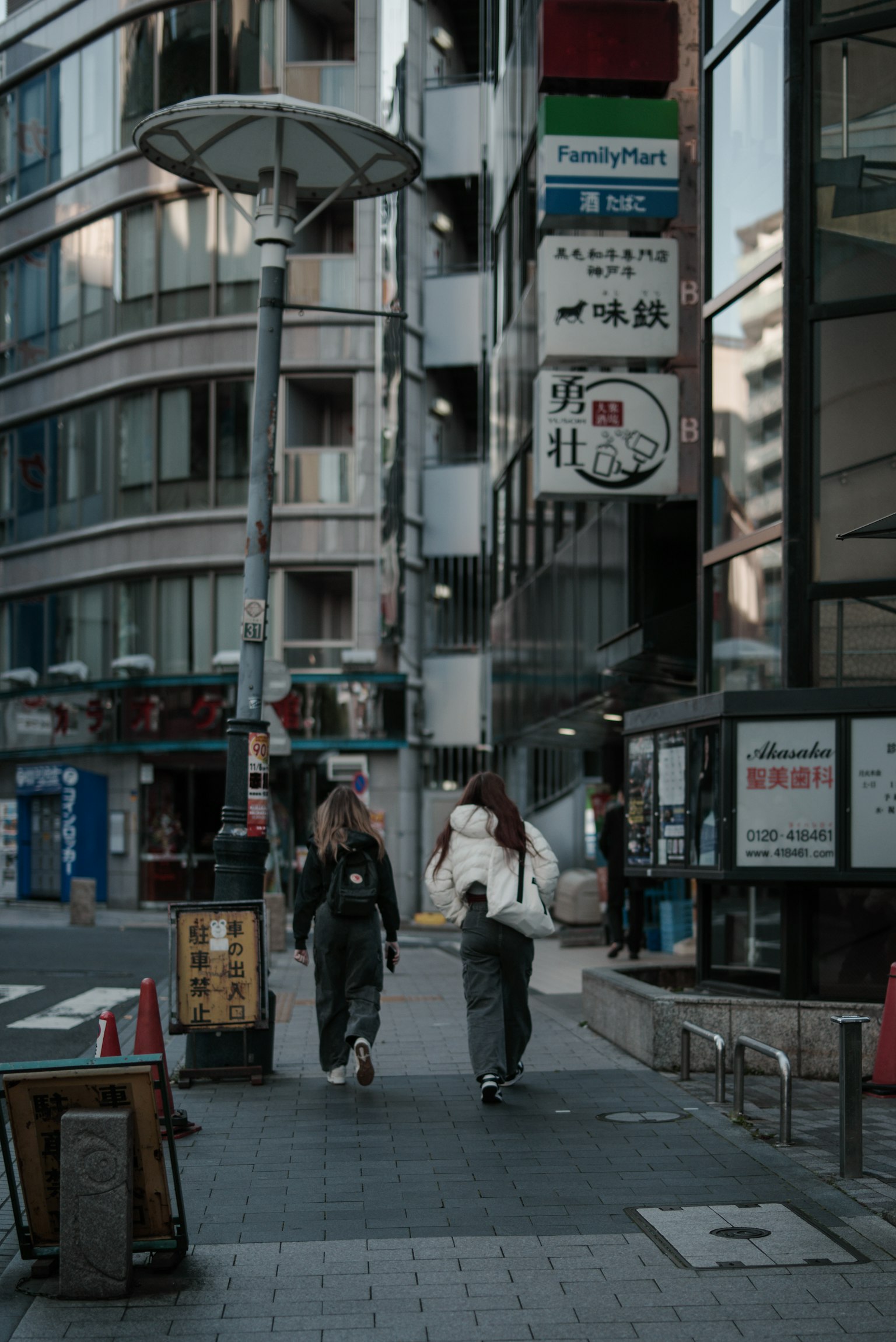 两位穿着和服的女性在现代建筑背景的城市街道上行走
