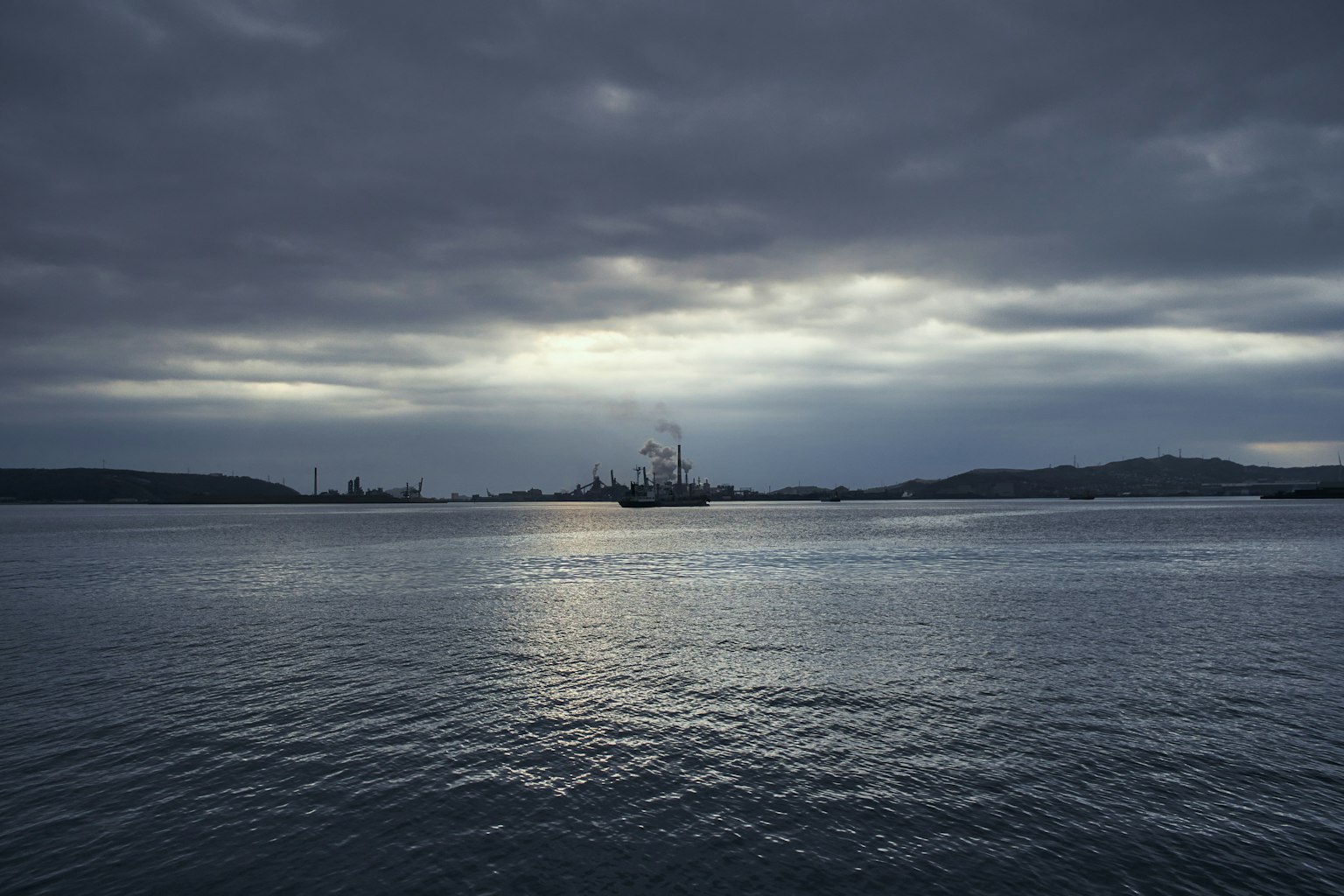 Serene sea view under a dark sky with distant ships