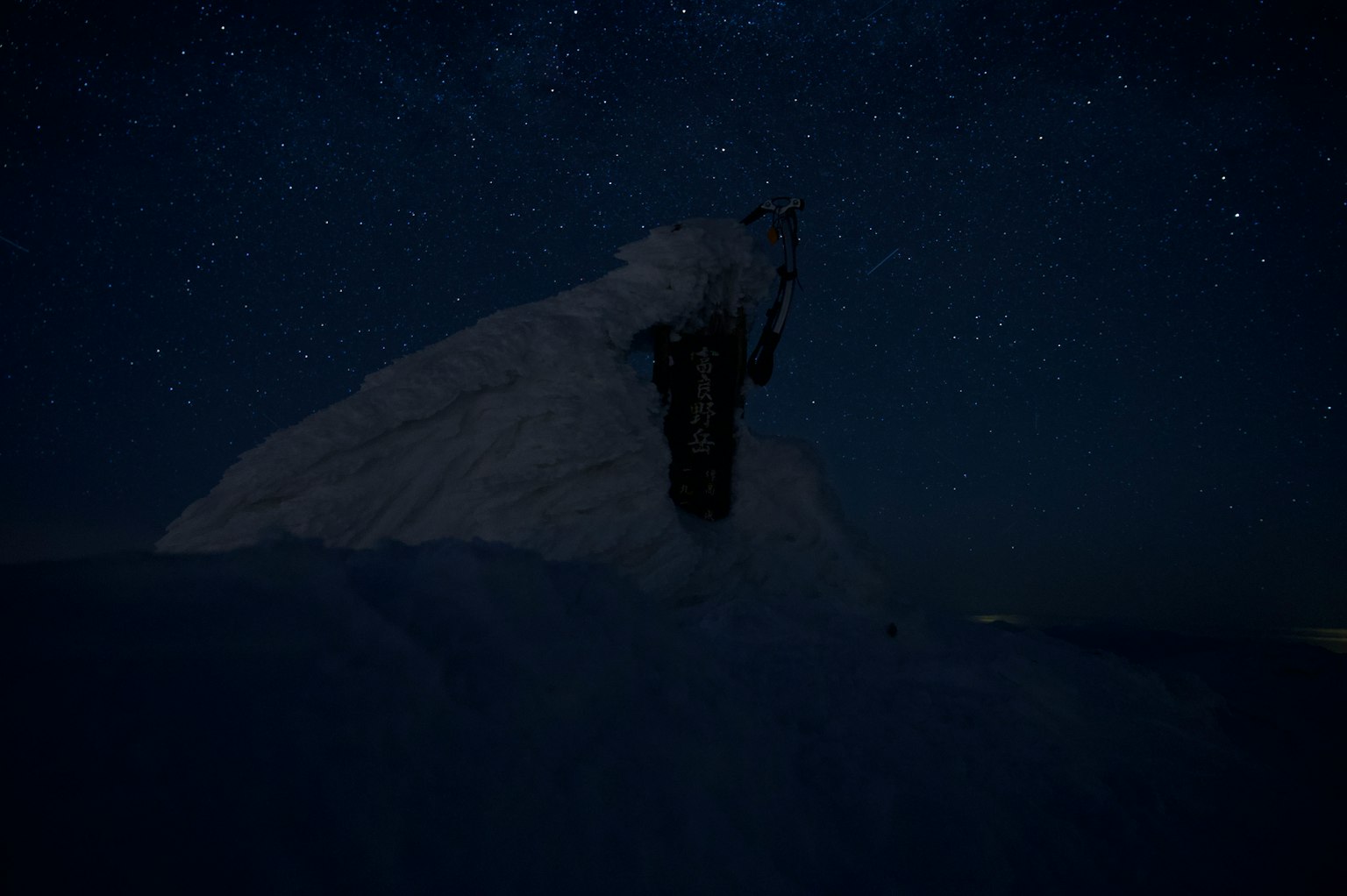 Silhouette d'une montagne enneigée sous un ciel étoilé