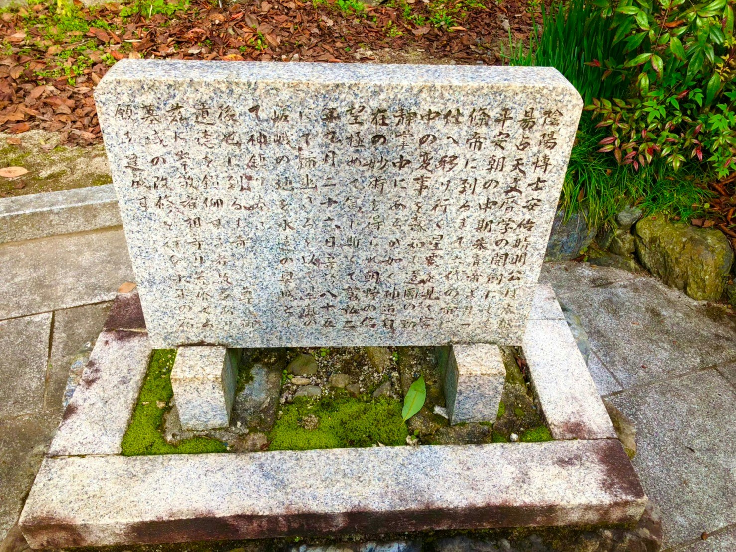 stone memorial tablet with engraved text beside a small water basin